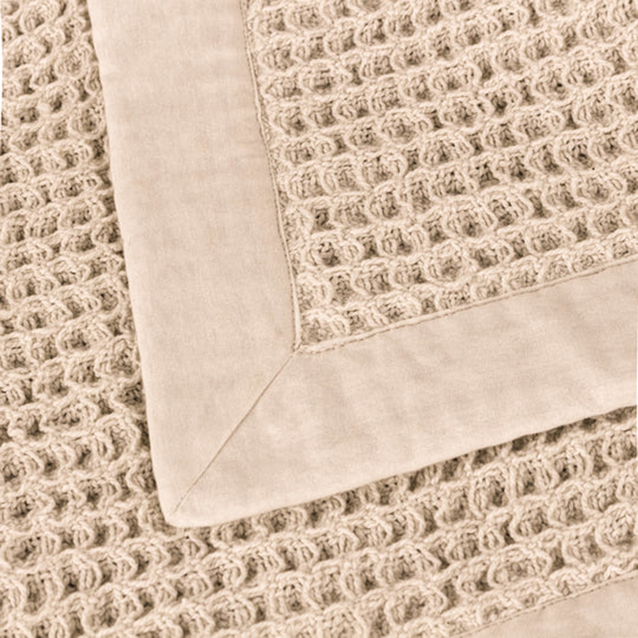Close-up of the Léna stone and natural cotton throw showing the textured waffle weave, smooth contrasting border and neatly mitred corner detailing.