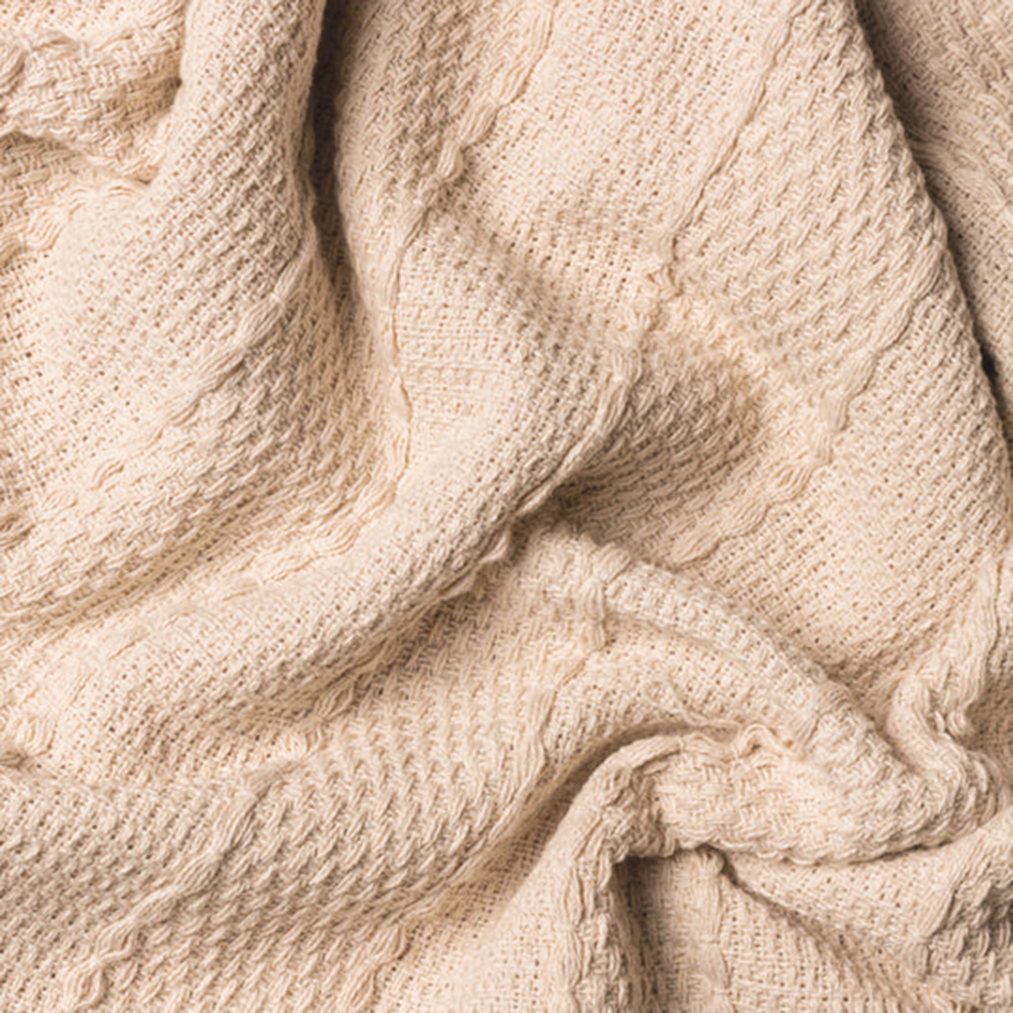 Close-up of the Léna Woven Cotton Tasselled Throw in Natural Beige, highlighting its tactile textured weave, subtle woven pattern and soft natural cotton appearance.