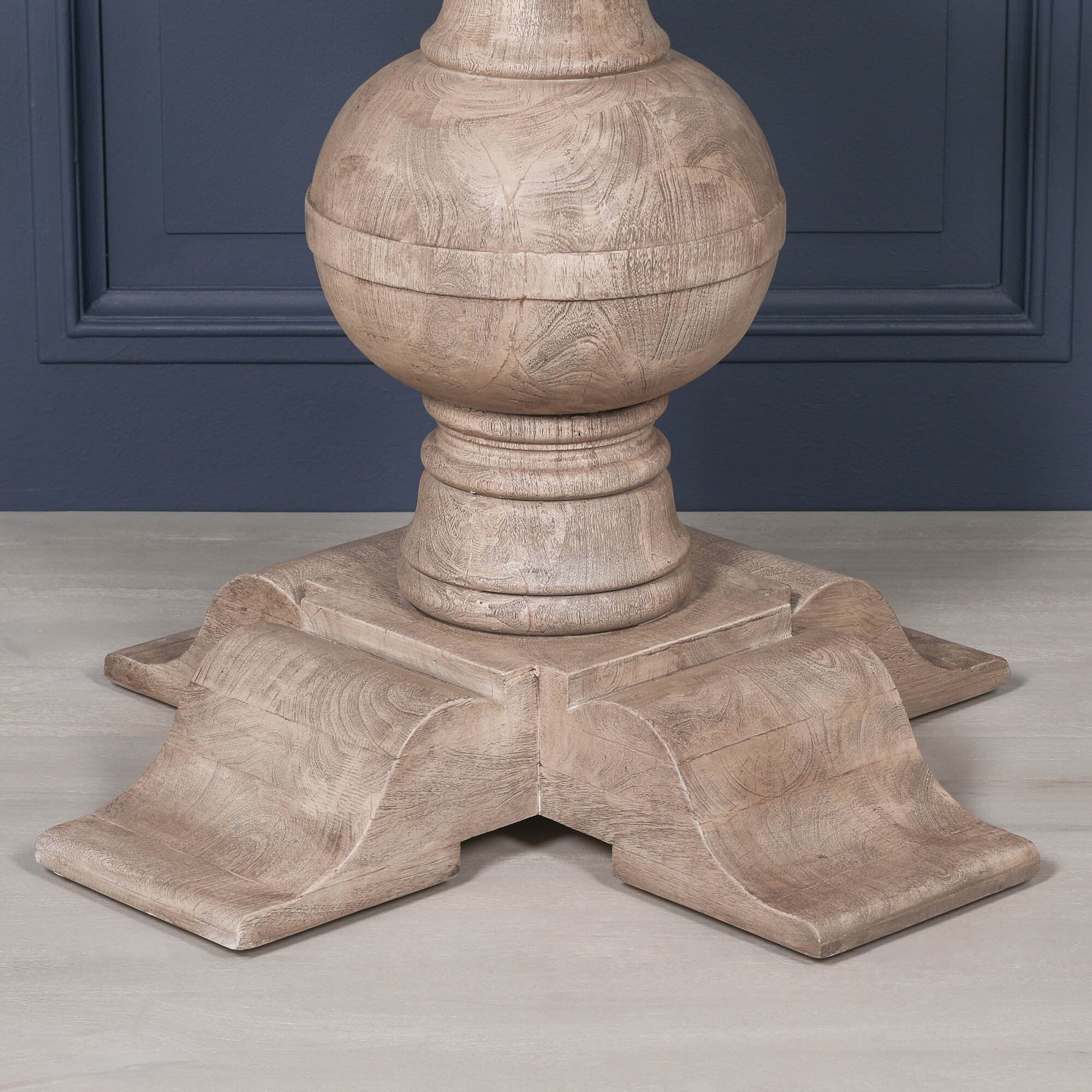 Detailed close-up of the Lucan dining table's handcrafted pedestal base, showcasing the turned ball column, solid acacia wood grain, rustic washed finish and substantial four-footed support designed for lasting stability and timeless character.