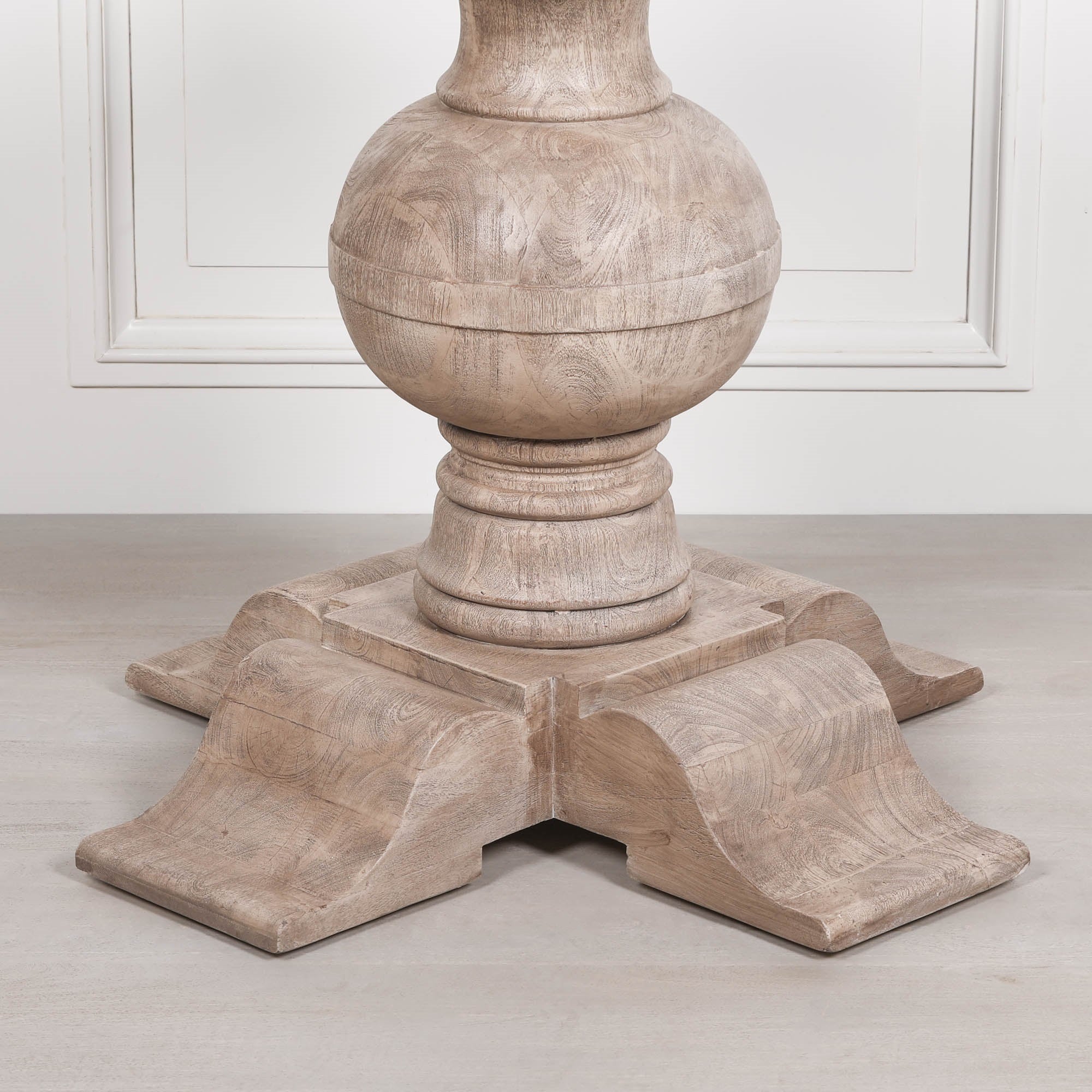 Close-up of the Lucan dining table pedestal base highlighting the handcrafted turned ball pedestal, solid acacia wood construction, natural wood grain and substantial four-footed architectural base with rustic washed finish.