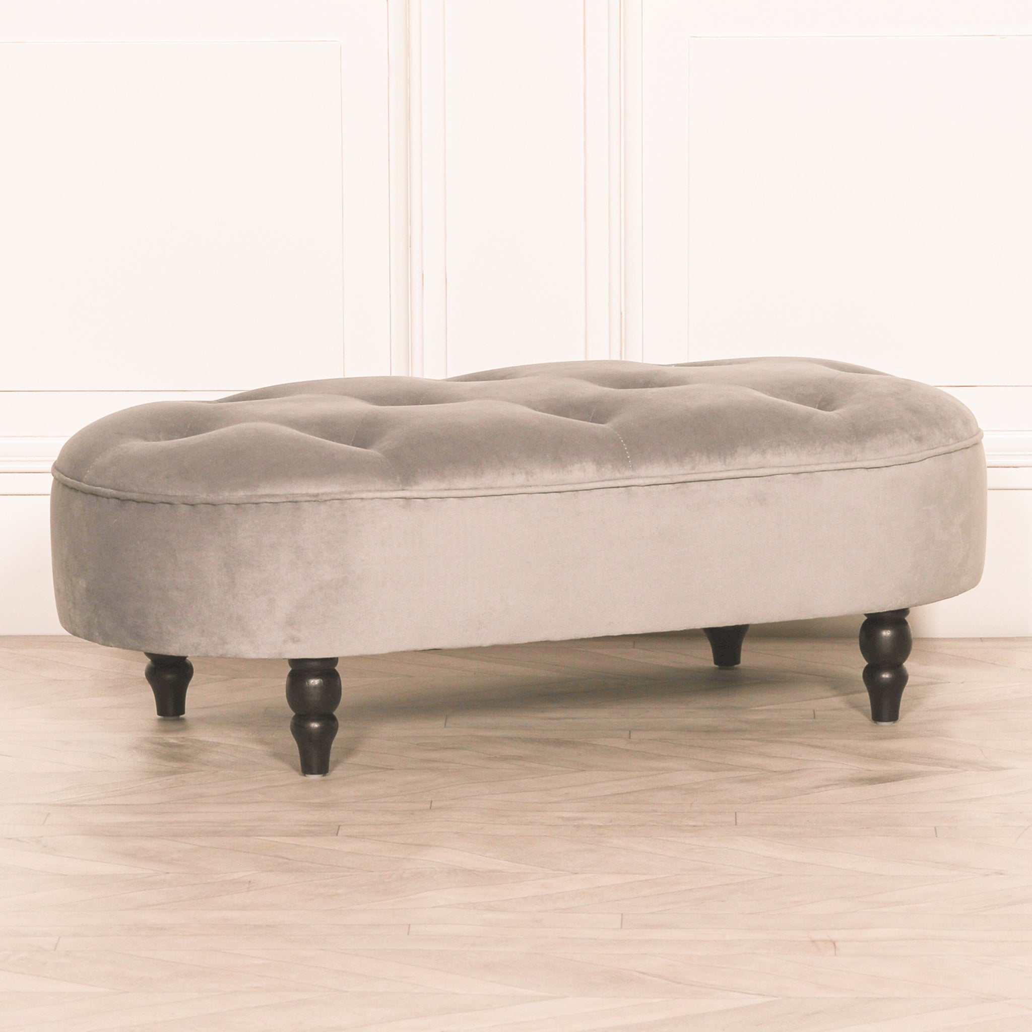 Side angle view of the Lucien Grey Velvet Upholstered Bedroom Bench with Black Legs, showcasing the curved upholstered silhouette, deep tufted velvet seat and elegant bedroom seating design.