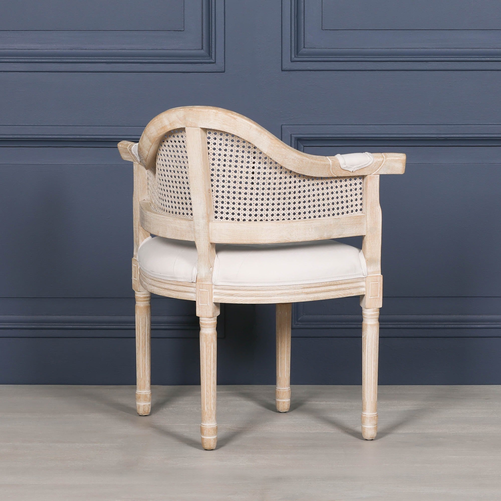 Rear angled view of the Lucienne Louis corner chair showcasing the curved woven cane back, washed wood frame and upholstered linen seat.
