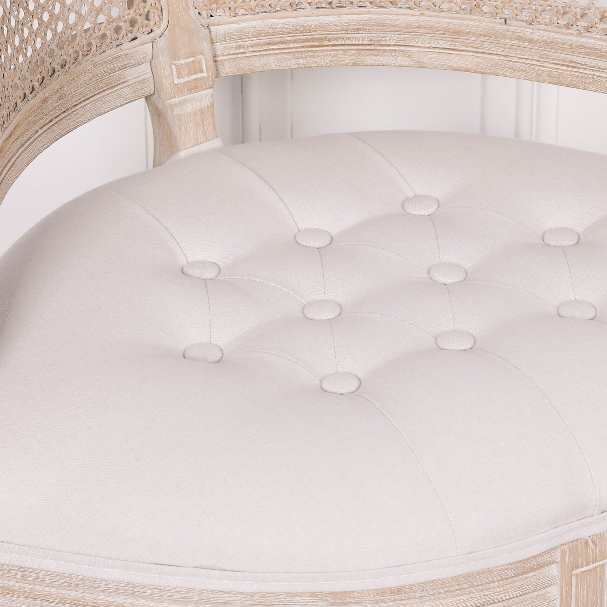 Close-up of the Lucienne Louis corner chair with button-tufted natural linen upholstered seat, washed wood frame and elegant French design details.