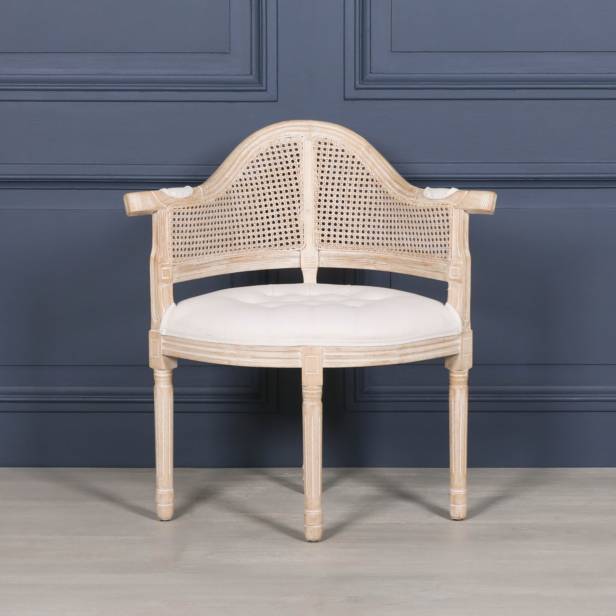 Full front view of the Lucienne Louis corner chair with hand-woven cane backrest, linen upholstery and washed wood frame inspired by classic French Louis furniture.
