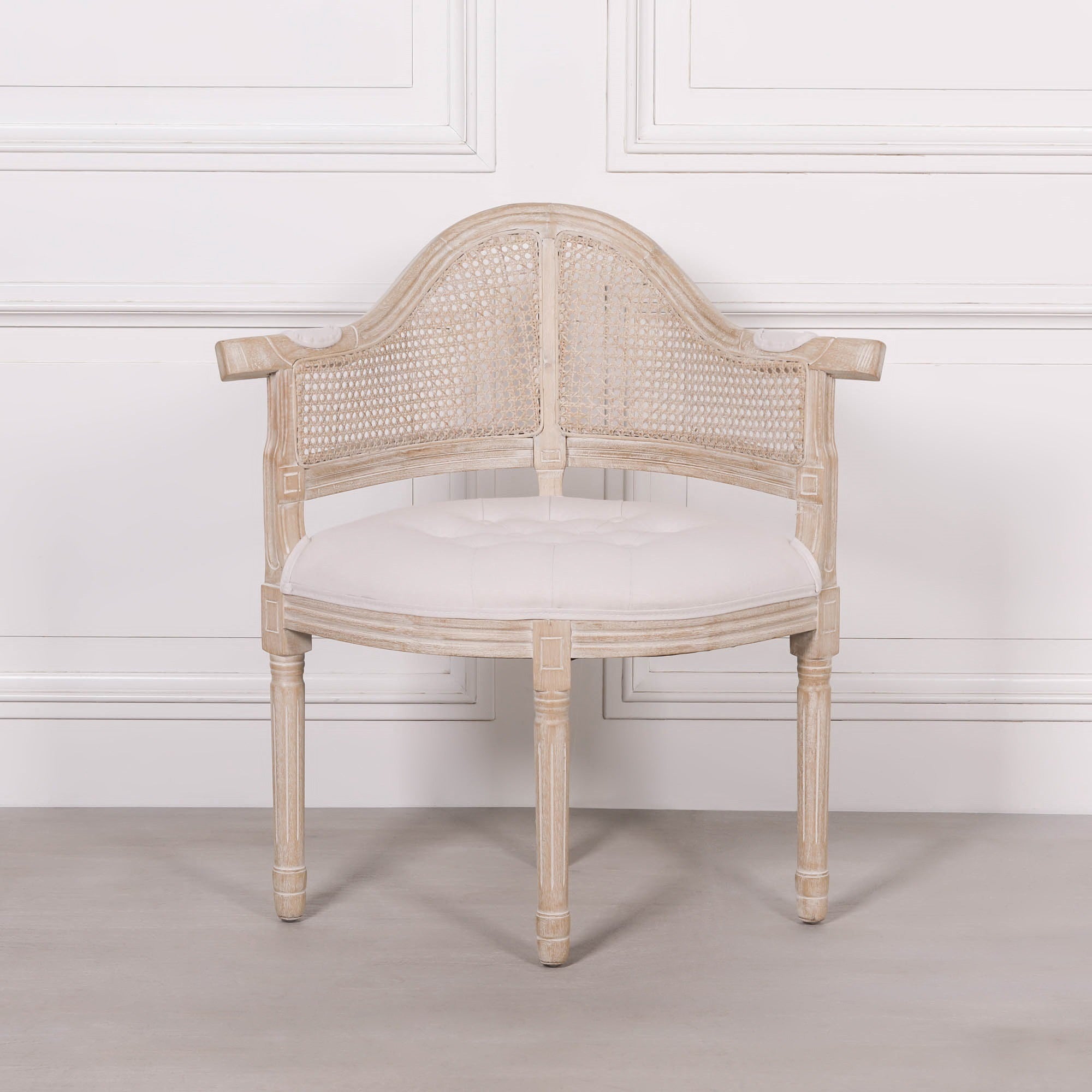 Front view of the Lucienne Louis corner chair with natural linen upholstery, woven cane backrest and distressed washed wood frame in a classic French Louis style.