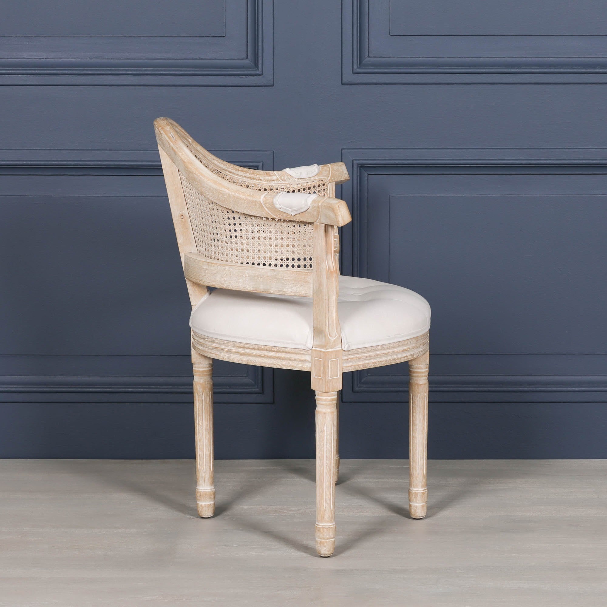 Side profile of the Lucienne Louis corner chair highlighting its curved cane backrest, linen upholstered seat and elegant washed wood frame.