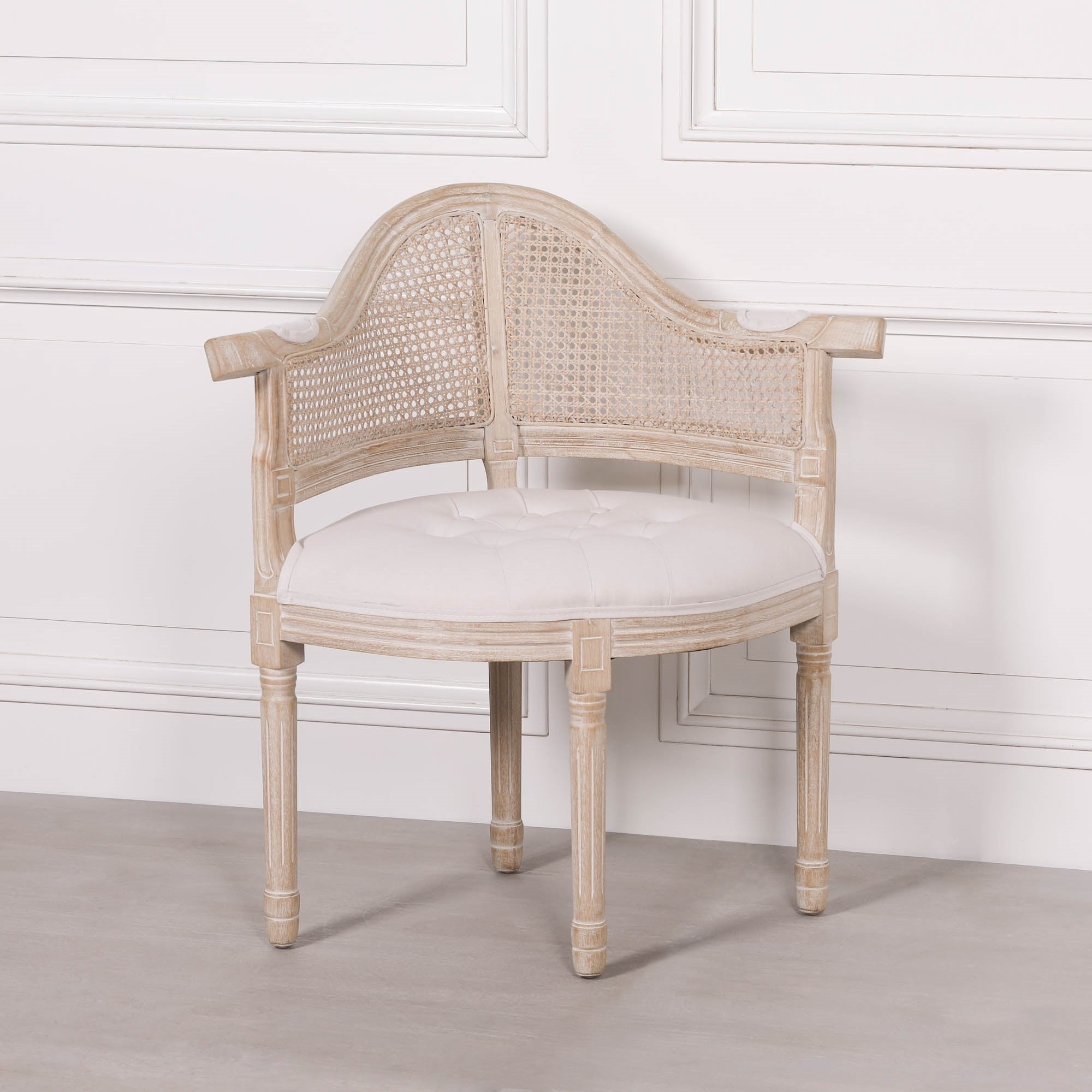 Three-quarter front view of the Lucienne Louis corner chair featuring linen upholstery, woven cane detailing and a washed wood frame for timeless French interiors.