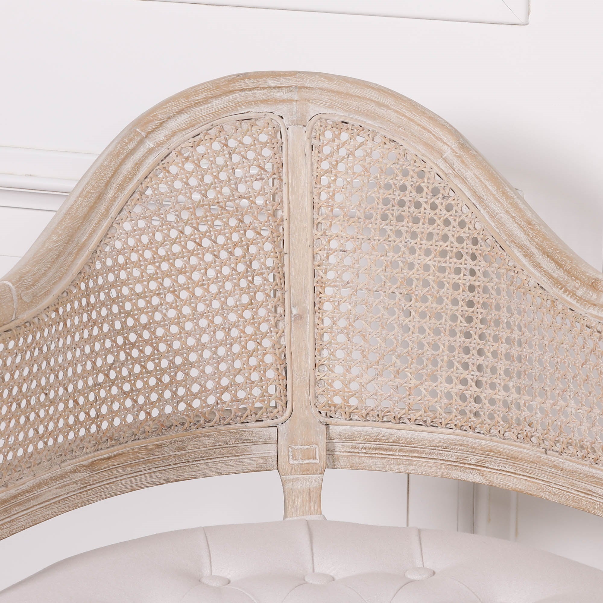 Close-up of the Lucienne Louis corner chair showcasing the arched woven cane backrest and distressed washed wood frame with handcrafted detailing.