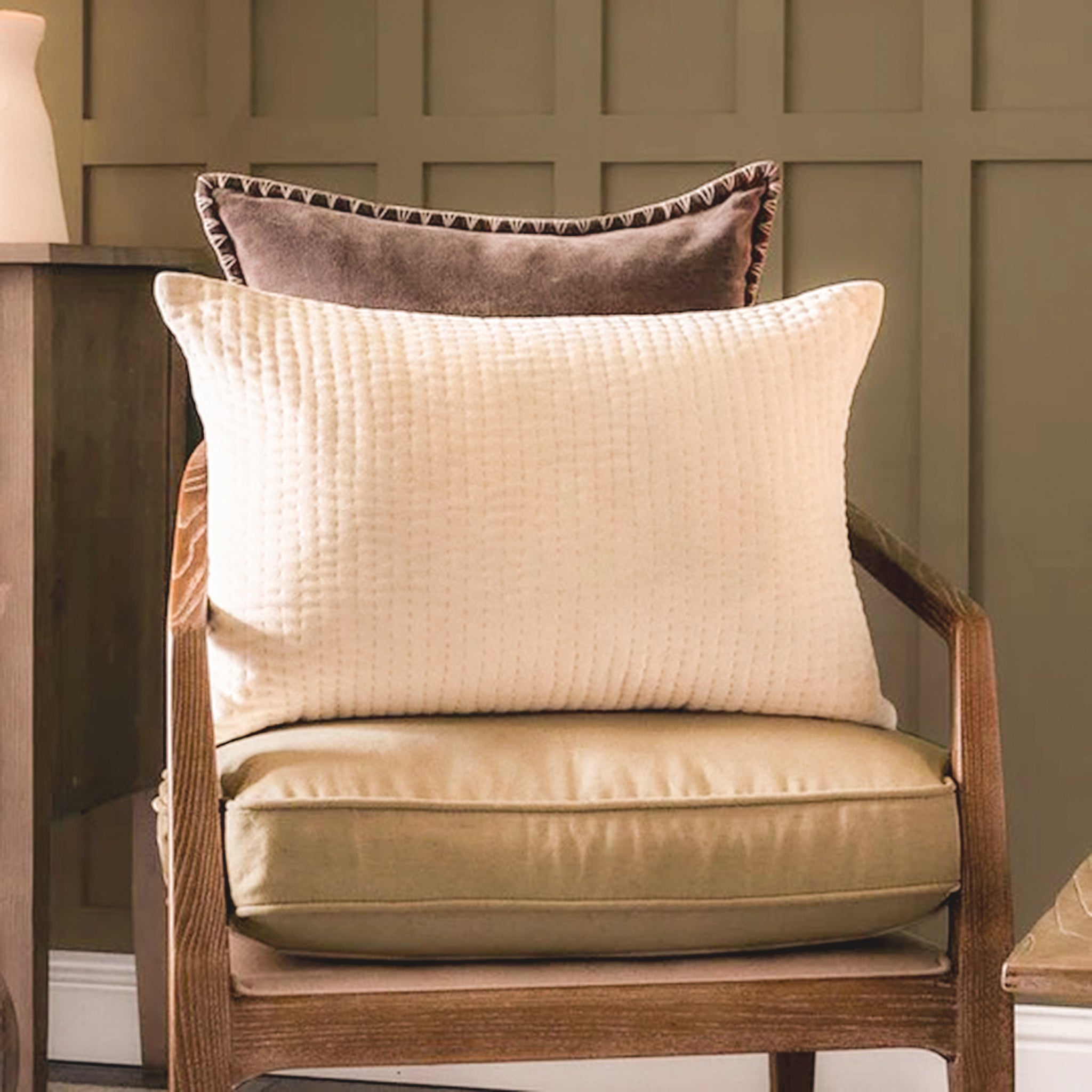 Maëva Embroidered Cotton Velvet Cushion in Quartz Ivory styled on a wooden accent chair with a contrasting velvet cushion, showcasing its soft embroidered texture and elegant neutral colour for luxury living room décor.