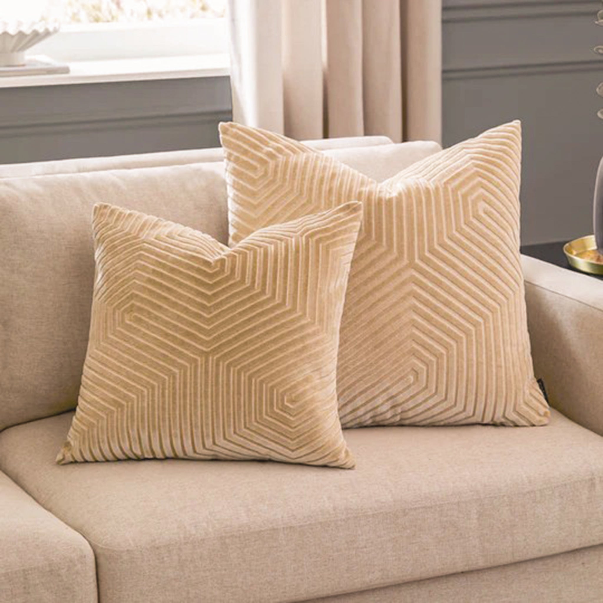 Maëva ivory geometric cut velvet cushions styled together on a neutral sofa, showcasing the sculptural linear pattern as luxury decorative cushions for a living room.