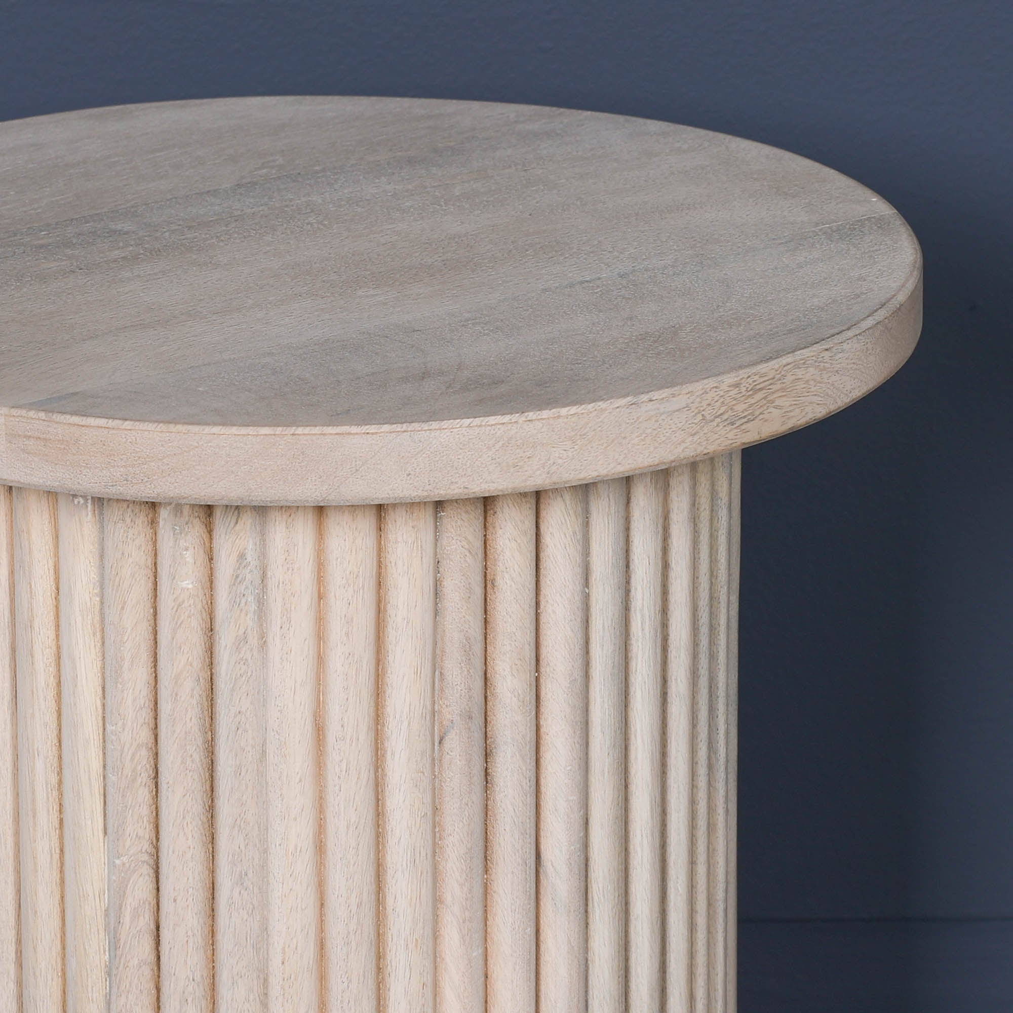 Close-up of the Margaux ribbed round side table showcasing the circular washed mango wood tabletop with natural wood grain and elegant fluted pedestal design for luxury contemporary homes.
