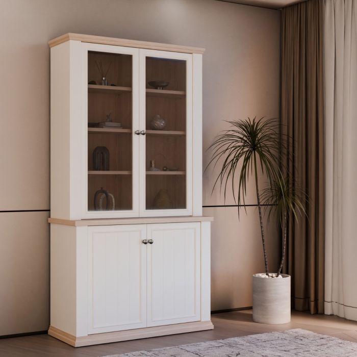 White cabinet with glass doors in a room with a plant and curtains.
