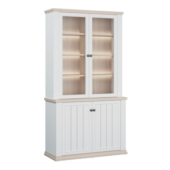 Angled view of the Montclair tall white and oak effect display cabinet with glazed doors, illuminated display shelving, panelled lower cupboards and metal handles.