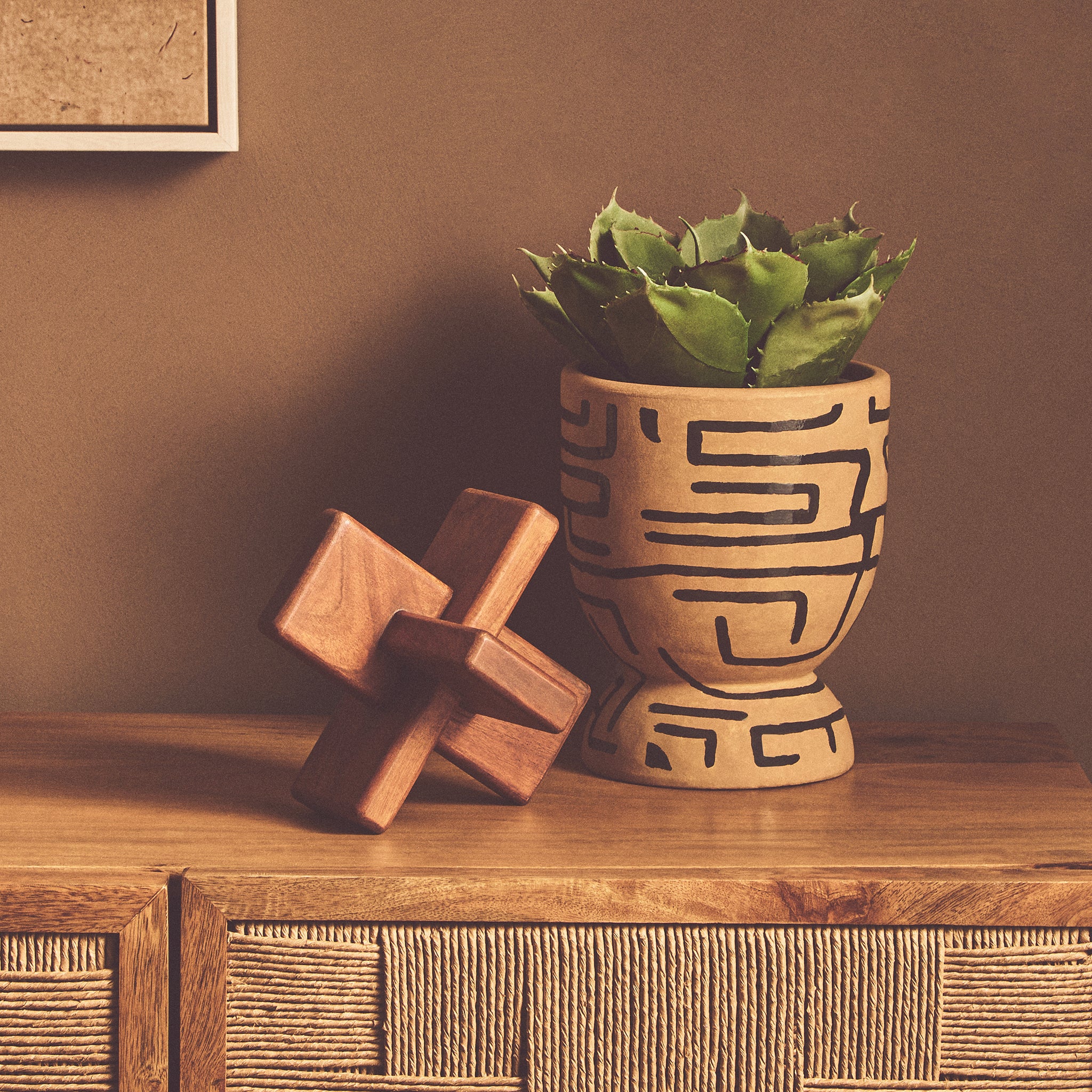Noé brown acacia wood decorative sculpture displayed beside a patterned planter on a wooden sideboard in a warm interior