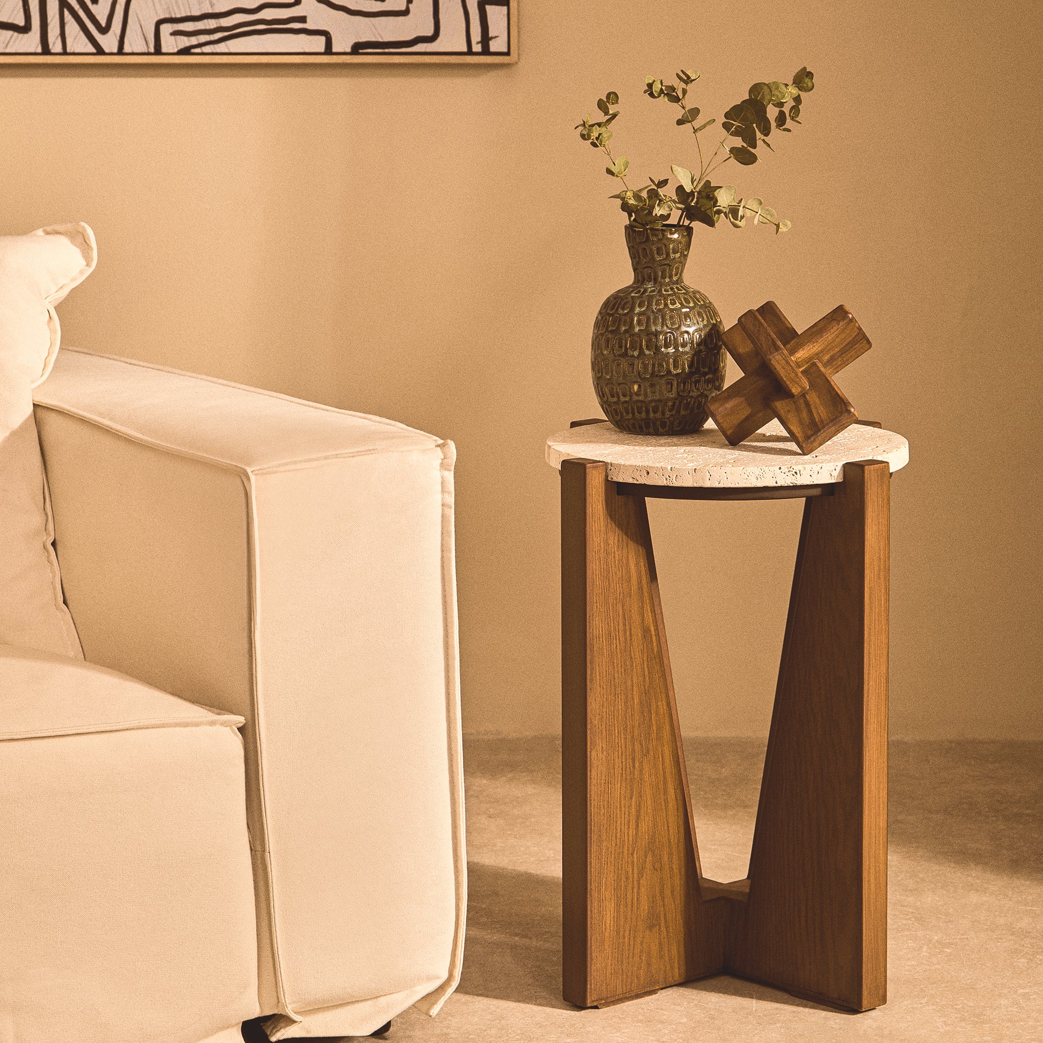 Noé brown acacia wood sculptural object styled with a vase on a small side table beside a cream sofa in a neutral living room