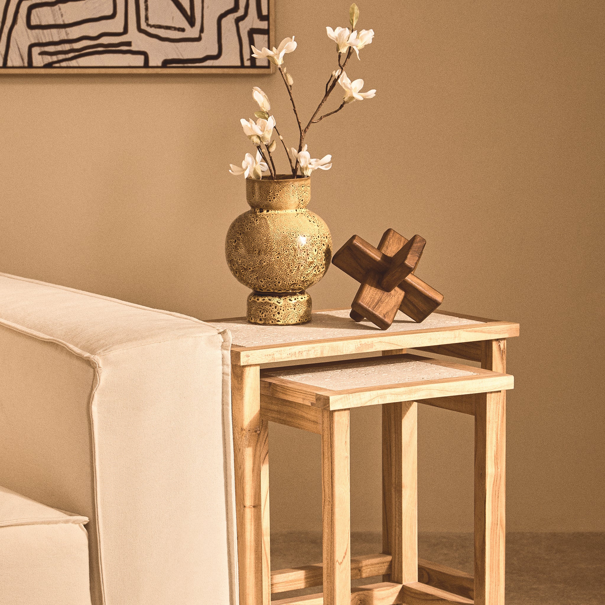 Noé brown acacia wood sculptural ornament displayed with a decorative vase on nesting side tables beside a cream sofa