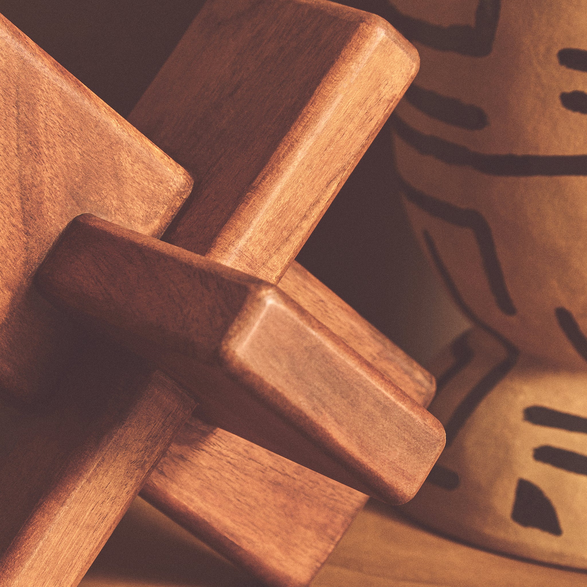 Close-up of the Noé hand-carved brown acacia wood sculptural object showing its smooth rounded edges, interlocking form and natural wood grain