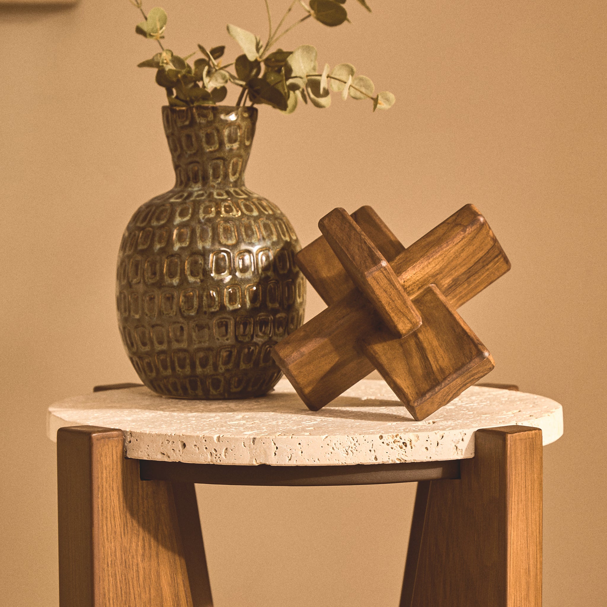 Noé hand-carved brown acacia wood sculptural object styled beside a decorative vase on a round stone-topped side table