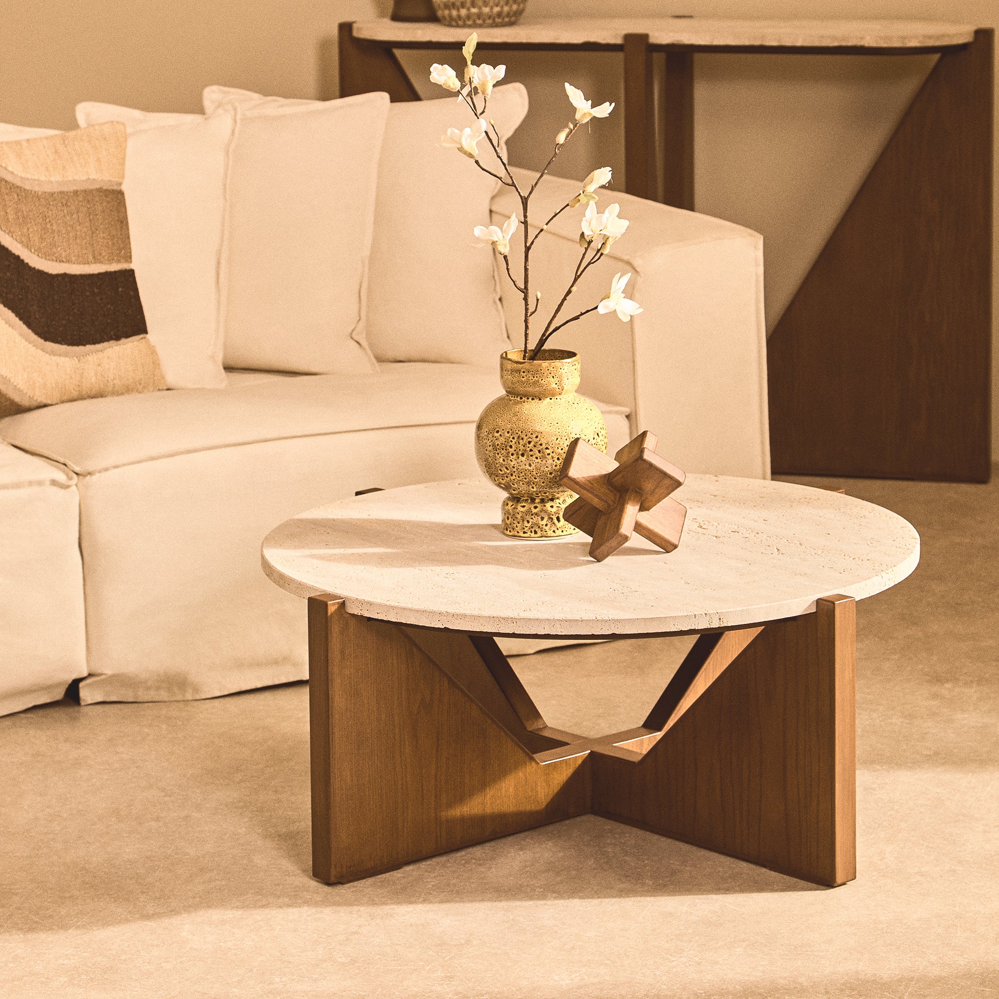 Noé hand-carved brown acacia wood sculptural object styled with a decorative vase on a round coffee table in a neutral living room