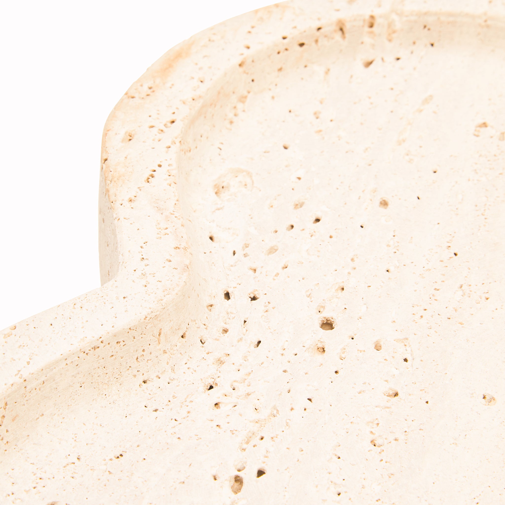 Close-up of the Noé Travertine Tray showing its softly curved raised rim, recessed surface and naturally porous warm beige travertine texture.