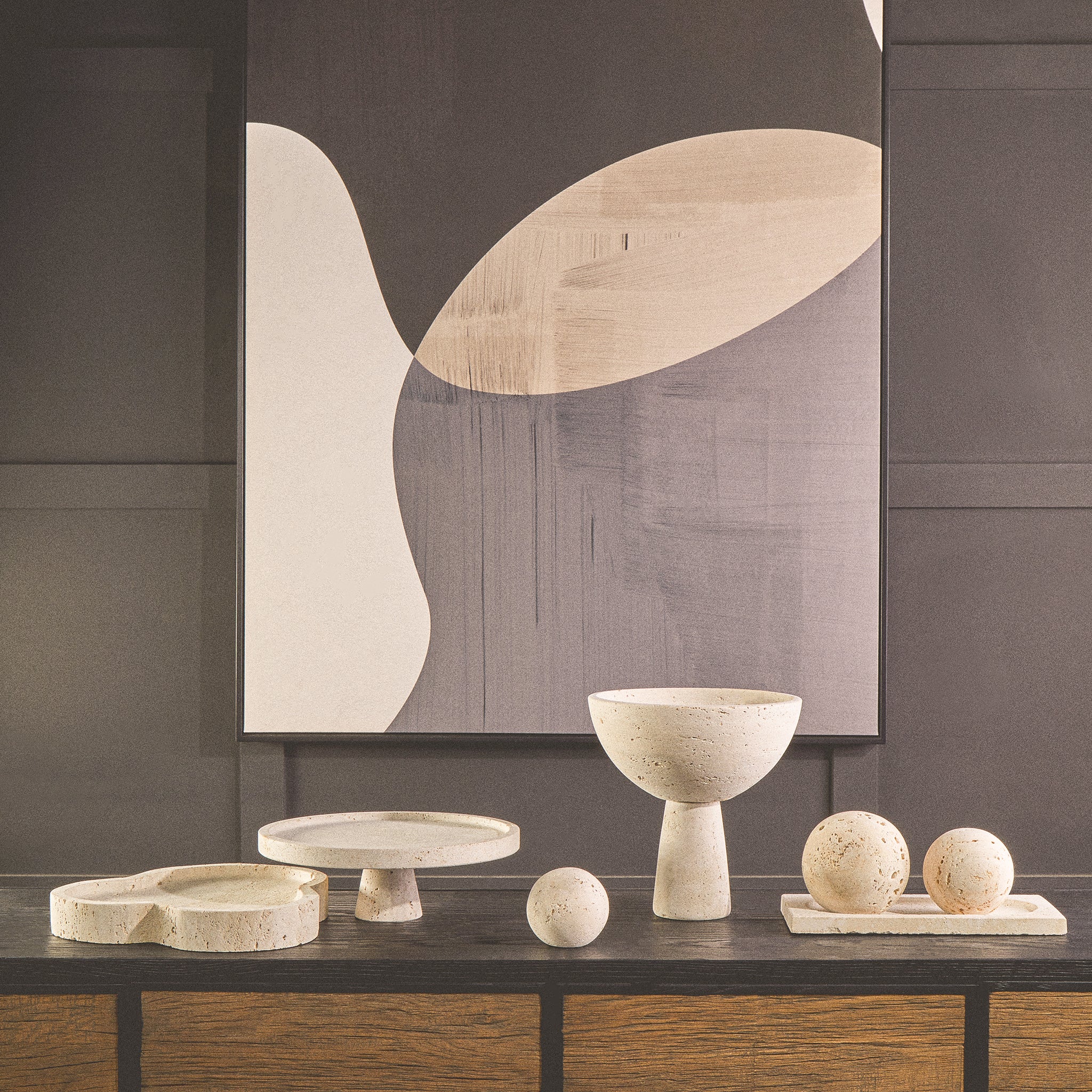 Noé Travertine Tray in an irregular organic stone form styled on a dark wood console with neutral sculptural home accessories and abstract wall art.