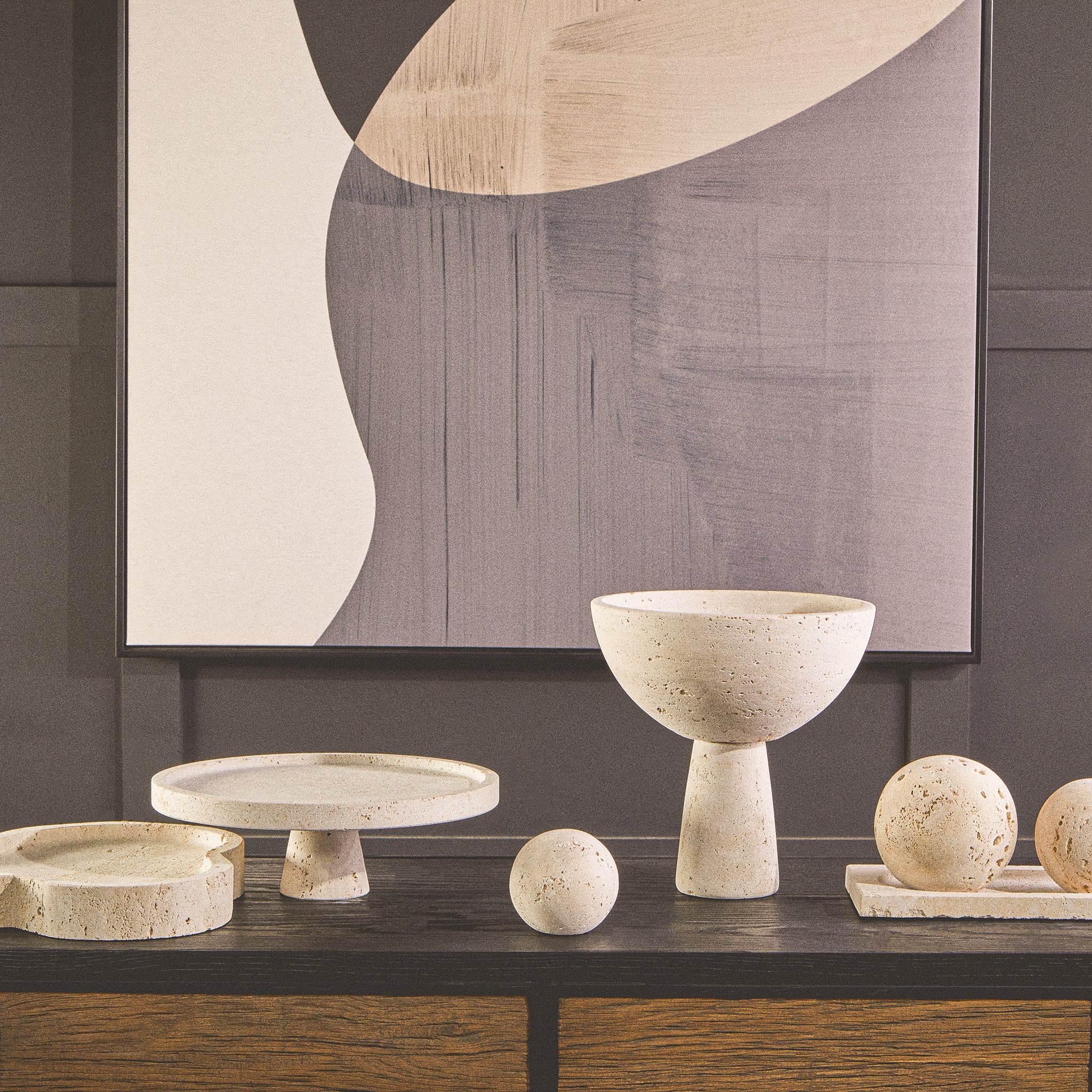 Noé Travertine Tray displayed with coordinating natural stone decorative objects on a dark wood console beneath contemporary abstract artwork.