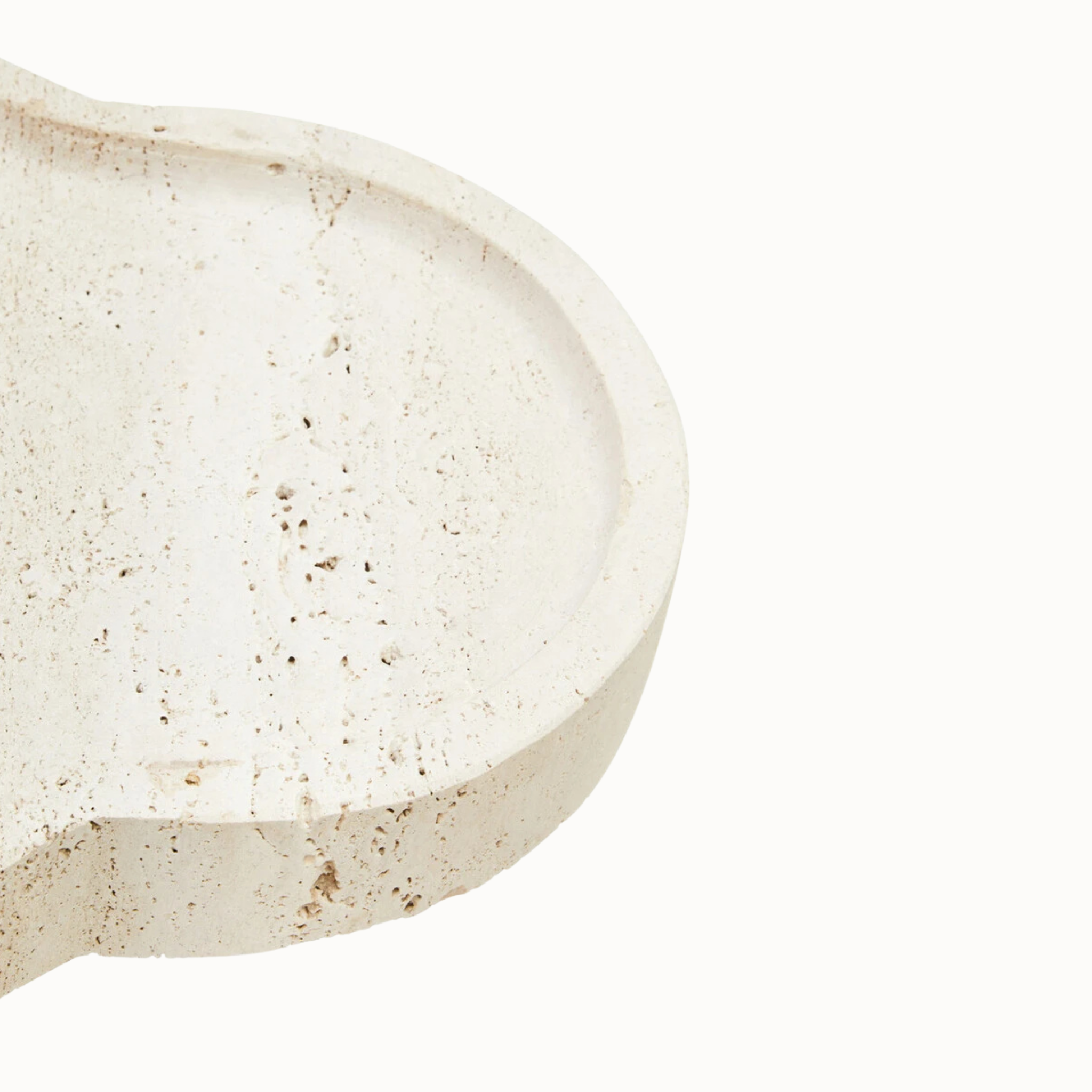Close-up of Noé travertine tray surface showing speckled beige stone, natural pits and curved rim on white.