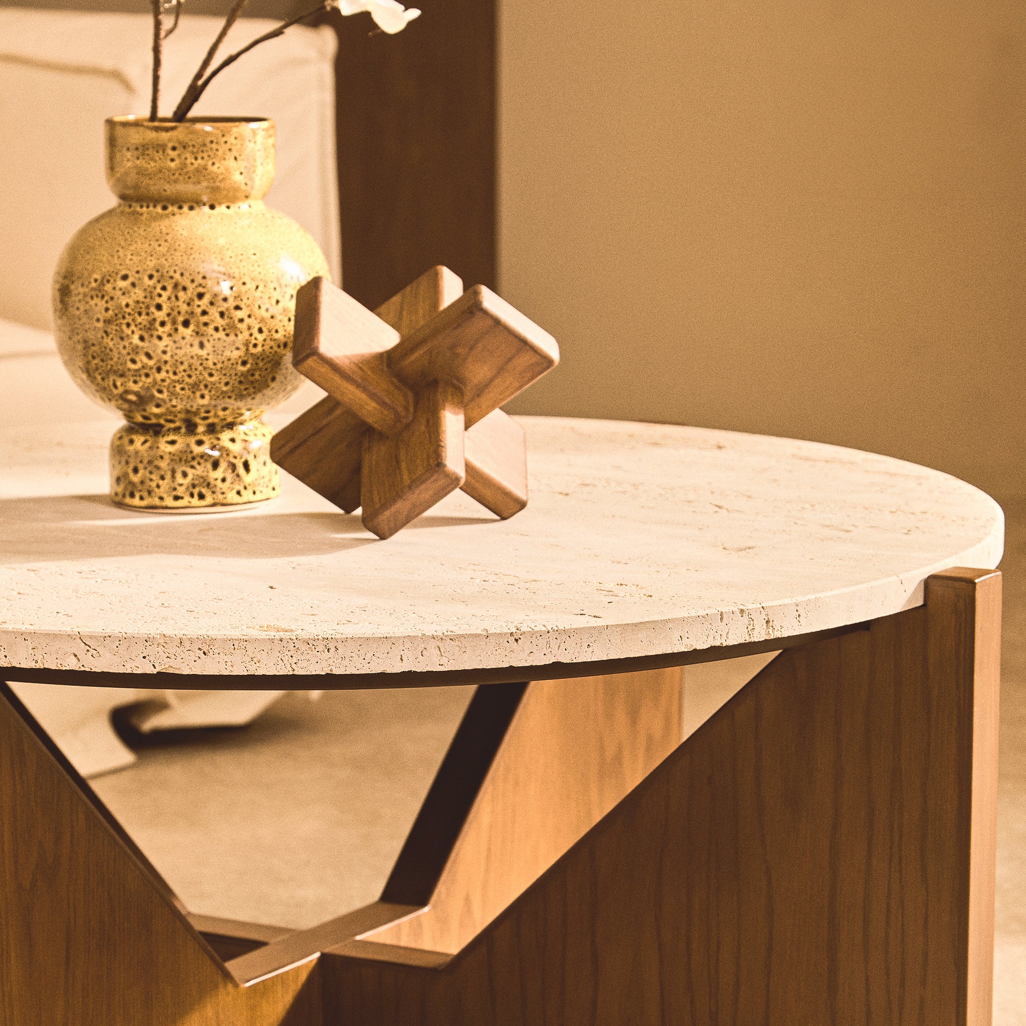 Noé hand-carved brown acacia wood sculptural object displayed beside a textured ceramic planter on a round stone coffee table