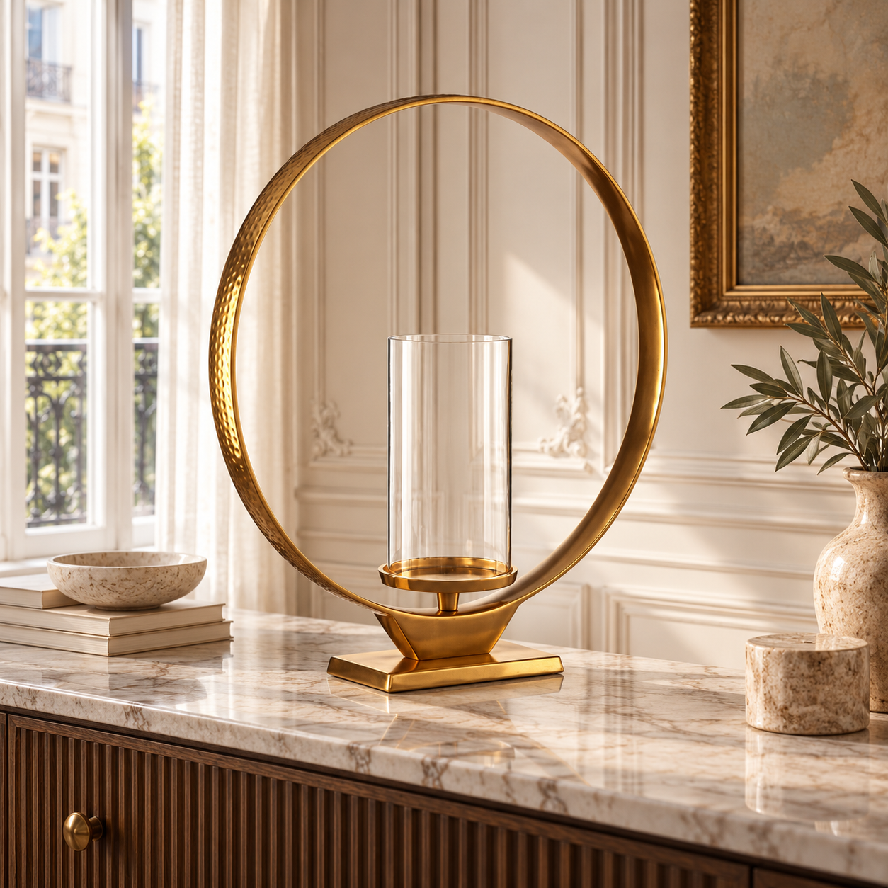 Octave 49cm gold aluminium loop candle holder with glass cylinder on a marble console in a sunlit Parisian room.