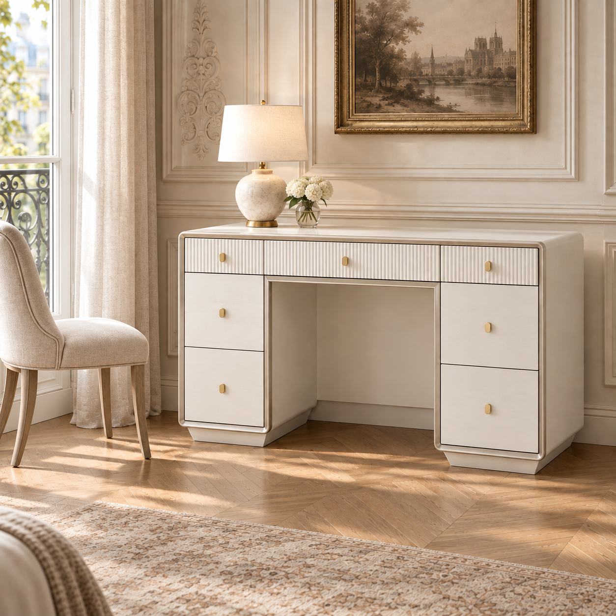 Oréliane ivory fluted 7 drawer dressing table with gold handles in a bright Parisian bedroom with chair, lamp and art.