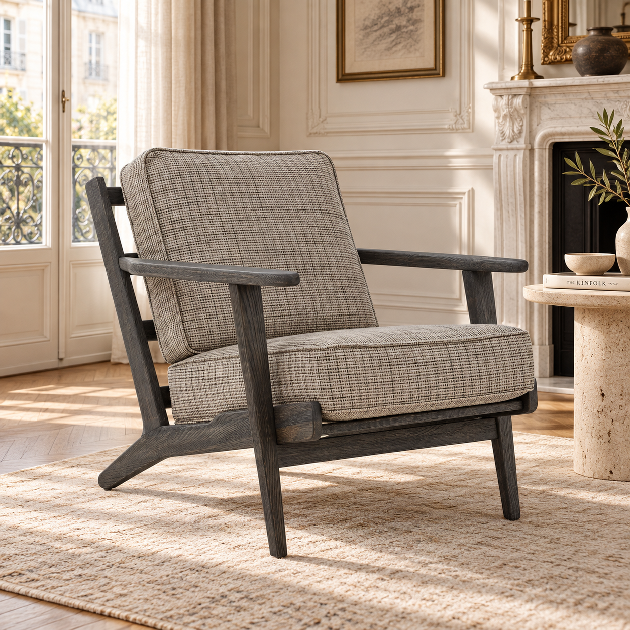 Rémi grey tweed armchair with black American oak frame in a sunlit Parisian living room with fireplace.