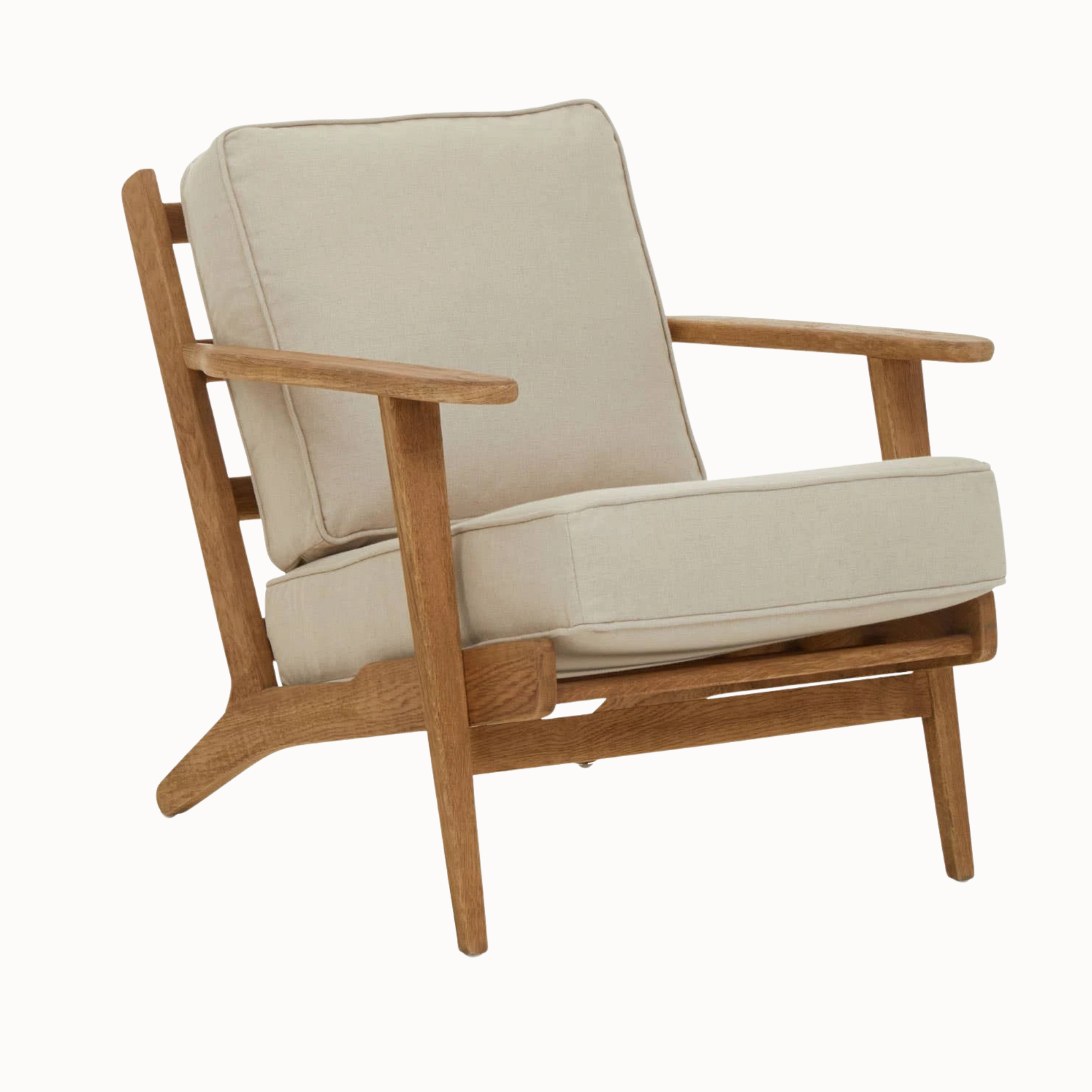Angled view of Rémi natural linen armchair with dark American oak wood frame on a plain white background.