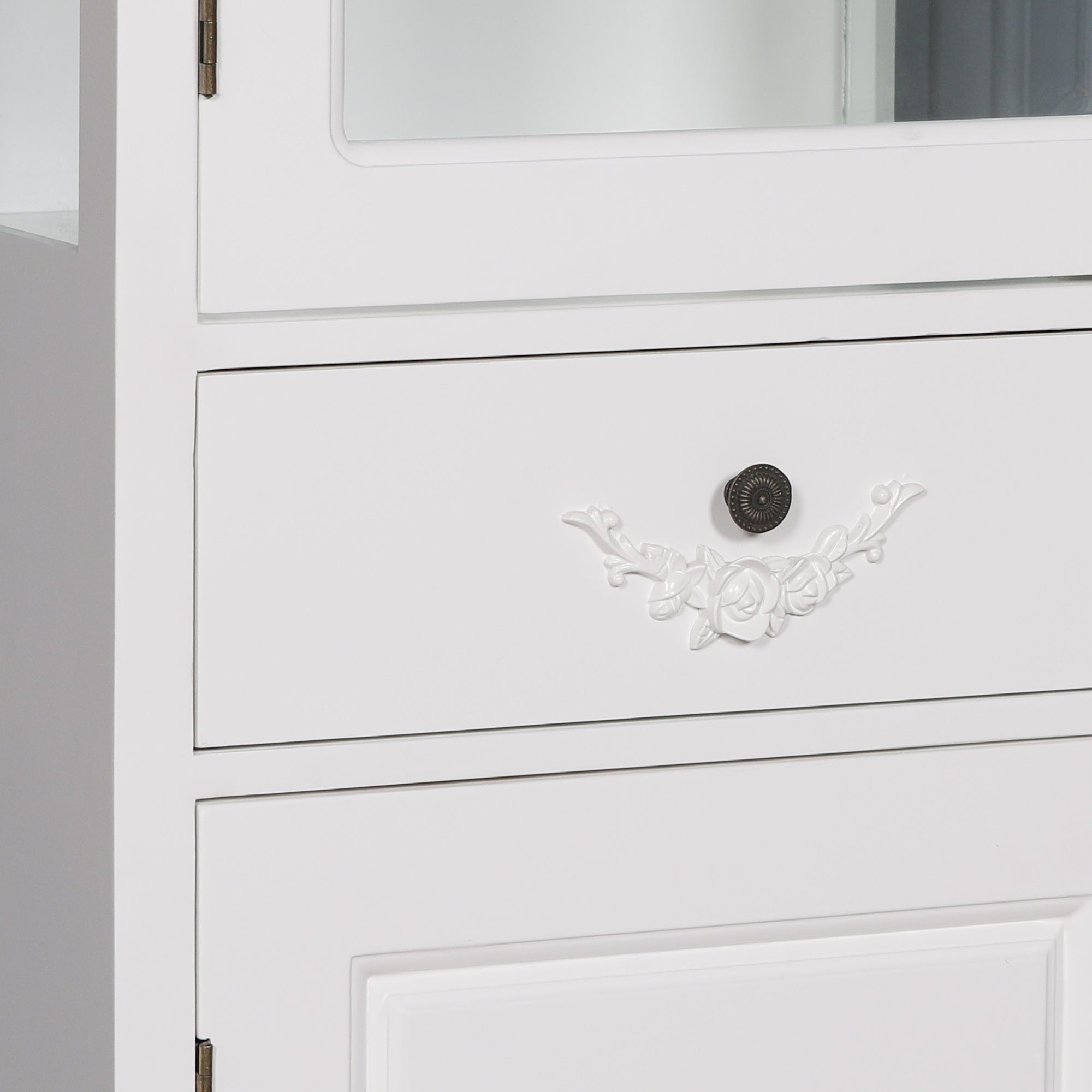 Detailed close-up of the decorative storage drawer on the Rosalie Tall French Glass Display Cabinet with Drawer in Antique White featuring elegant floral carvings, antique-style knob and handcrafted French furniture detailing.