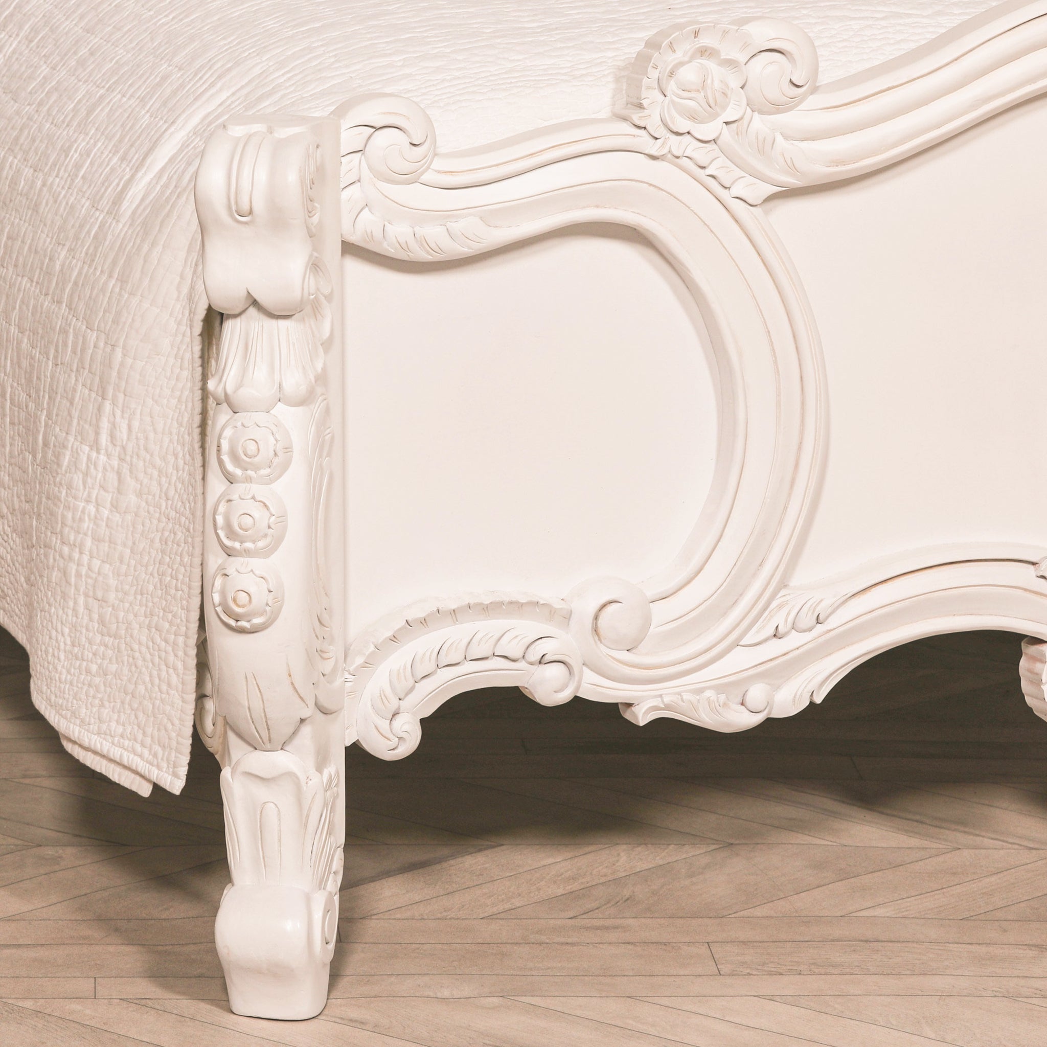 Close-up of the Rosalie French Rococo king size bed footboard showing the curved painted white frame, carved floral scrollwork and ornate cabriole-style leg