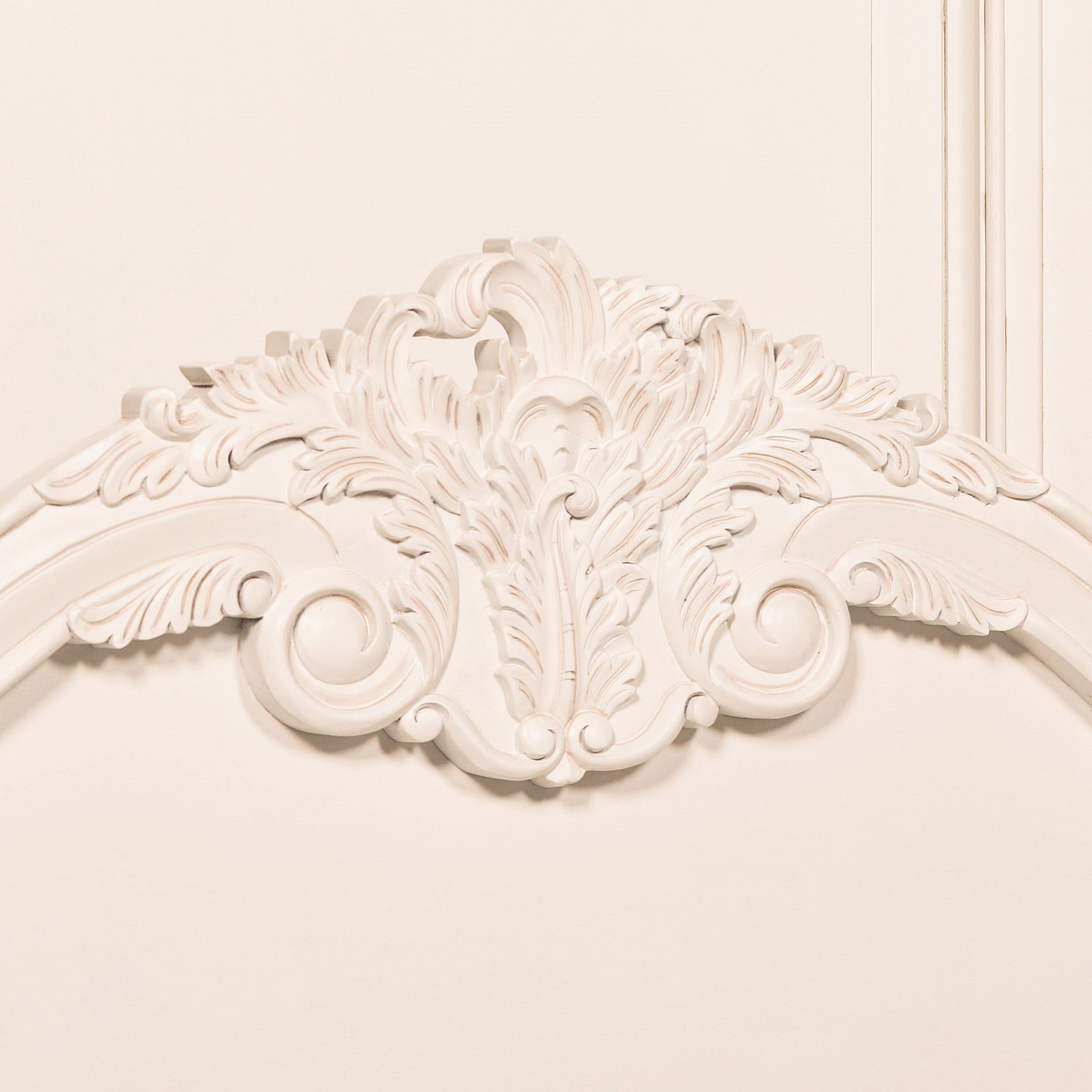 Close-up of the Rosalie French Rococo bed headboard showing intricate hand-carved cherub, foliage and scroll detailing in a light painted white finish