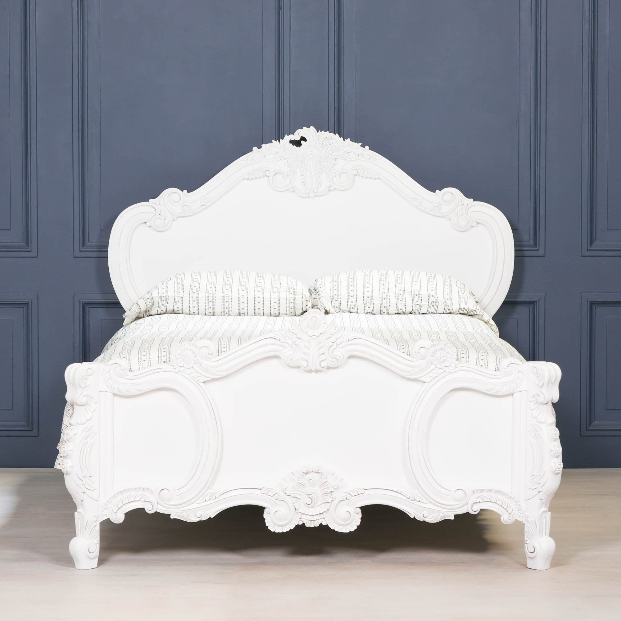 Rosalie French Rococo 4ft6 double bed frame in light painted white with luxurious hand-carved rose and cherub detailing styled against dark blue panelled walls.