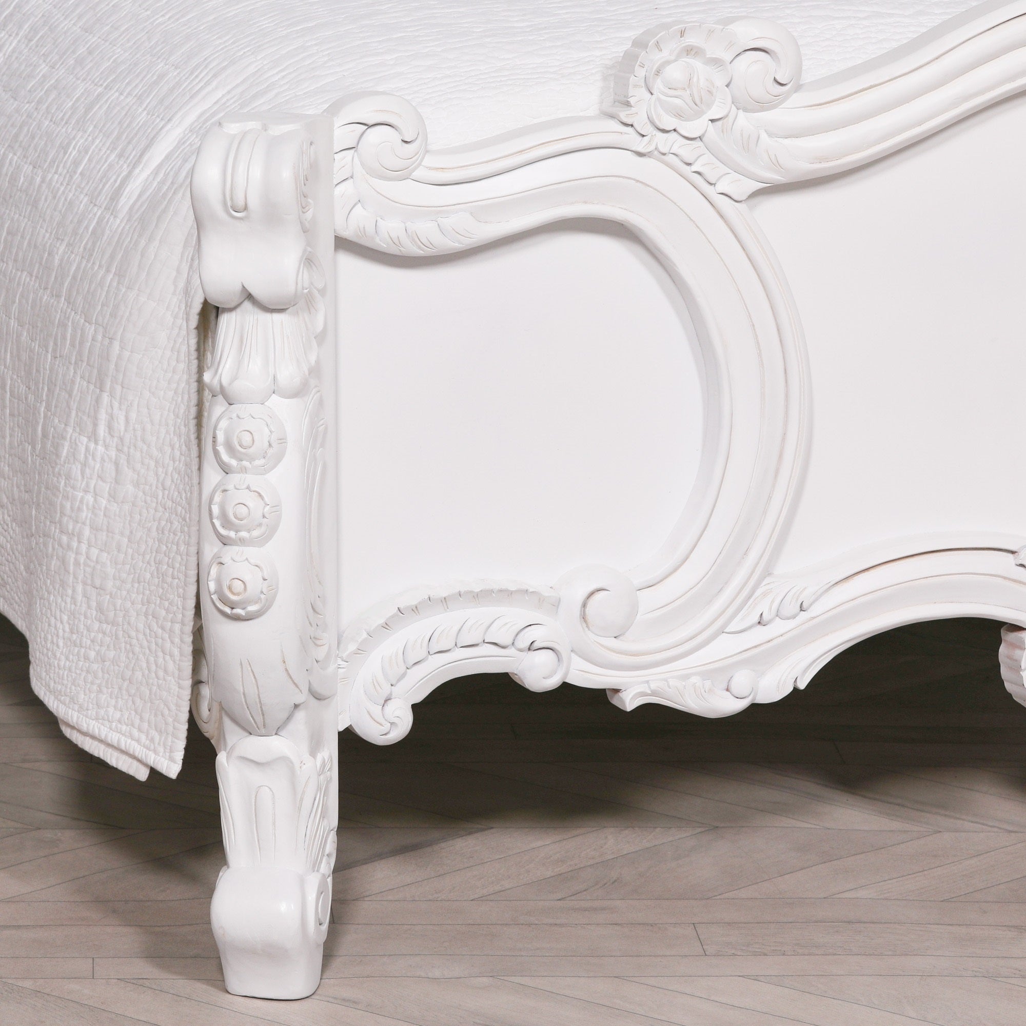 Close-up of the Rosalie French Rococo bed frame footboard featuring ornate hand-carved rose, cherub and scroll detailing in a light painted white finish.