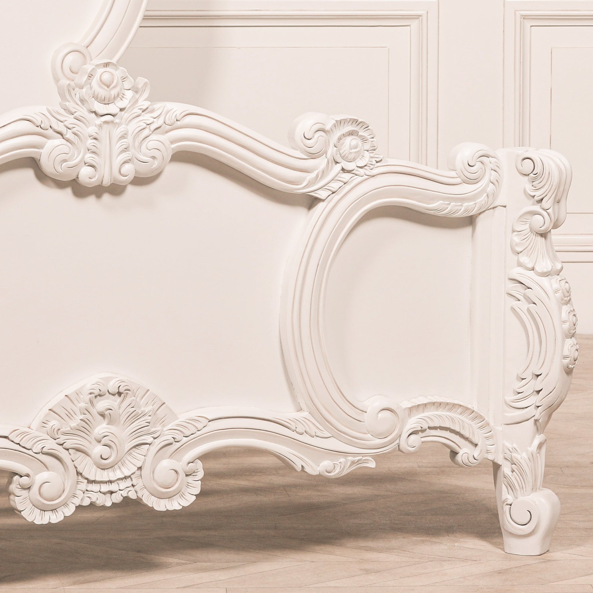 Detailed view of the Rosalie French Rococo king size bed footboard with ornate hand-carved floral motifs, sweeping scrollwork and sculpted painted white leg