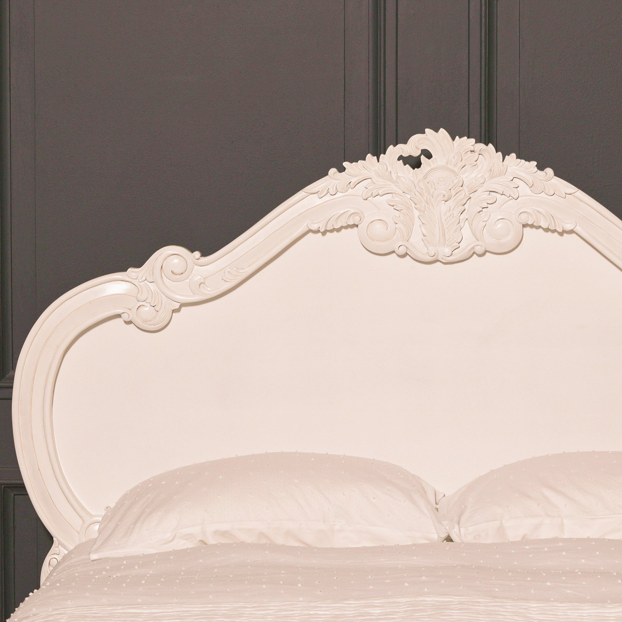 Ornate headboard of the Rosalie French Rococo 5FT king size bed in light painted white with hand-carved cherub, leaf and scroll detailing