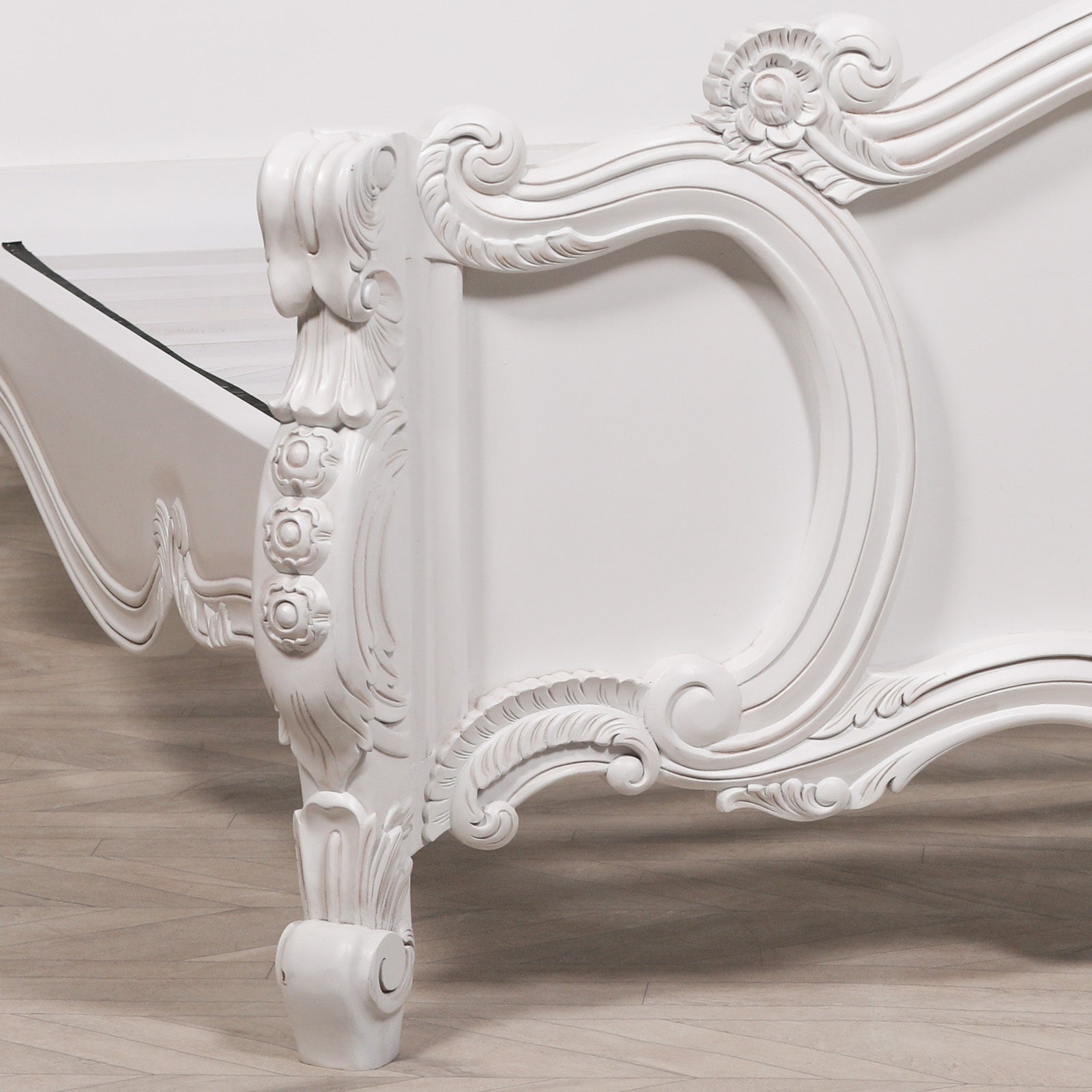 Side view of the Rosalie French Rococo double bed footboard highlighting hand-carved scrollwork, rose detailing and cabriole leg in a light painted white finish.