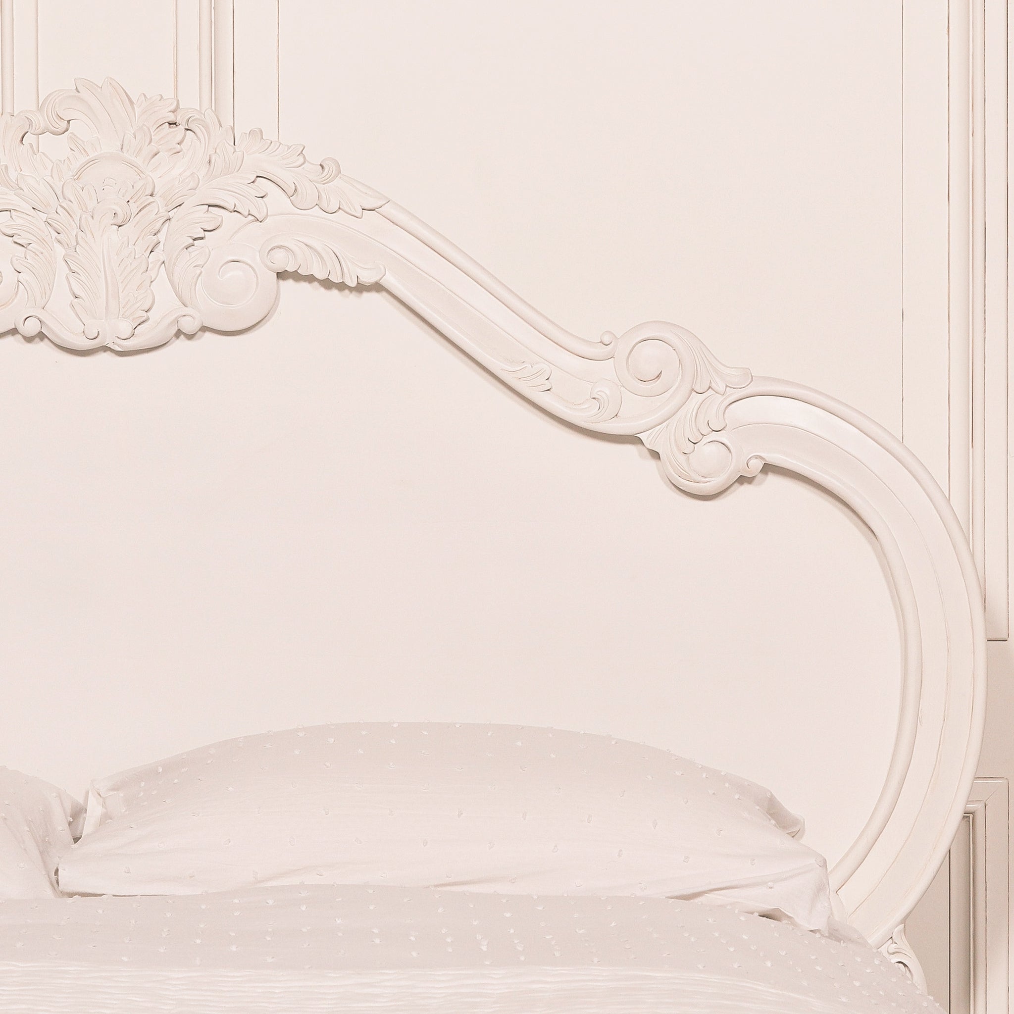 Close-up of the Rosalie French Rococo king size bed curved white headboard with ornate hand-carved scrollwork, floral motifs and decorative carved detailing