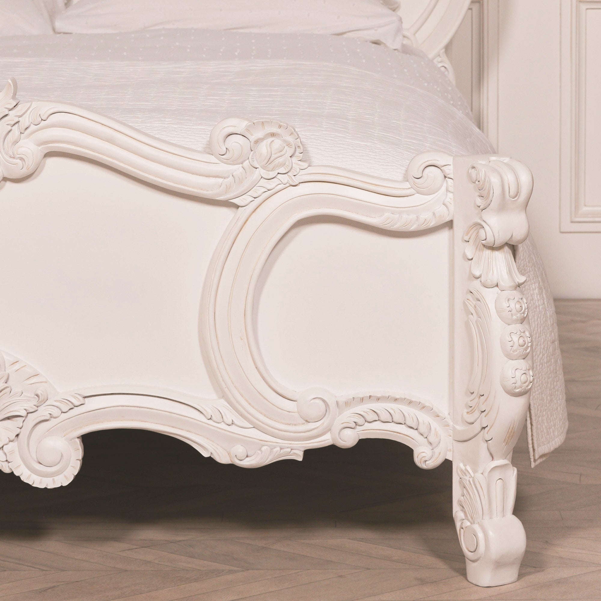 Detailed right-side view of the Rosalie French Rococo king size bed footboard with light painted white finish, carved floral motifs, scrollwork and decorative leg