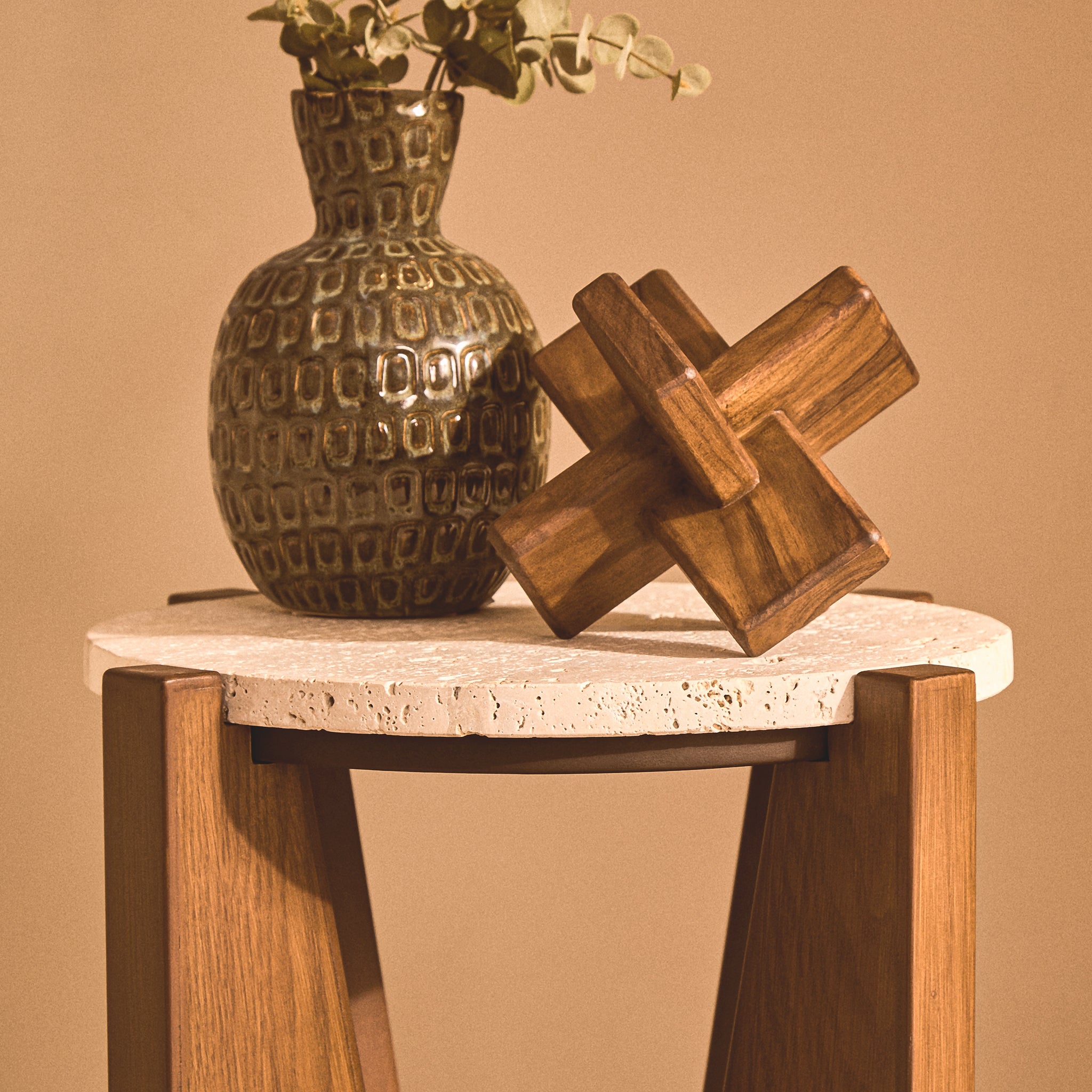 Soline travertine side table styled with a decorative ceramic vase and wooden ornament, showing its round stone top and warm acacia wood frame