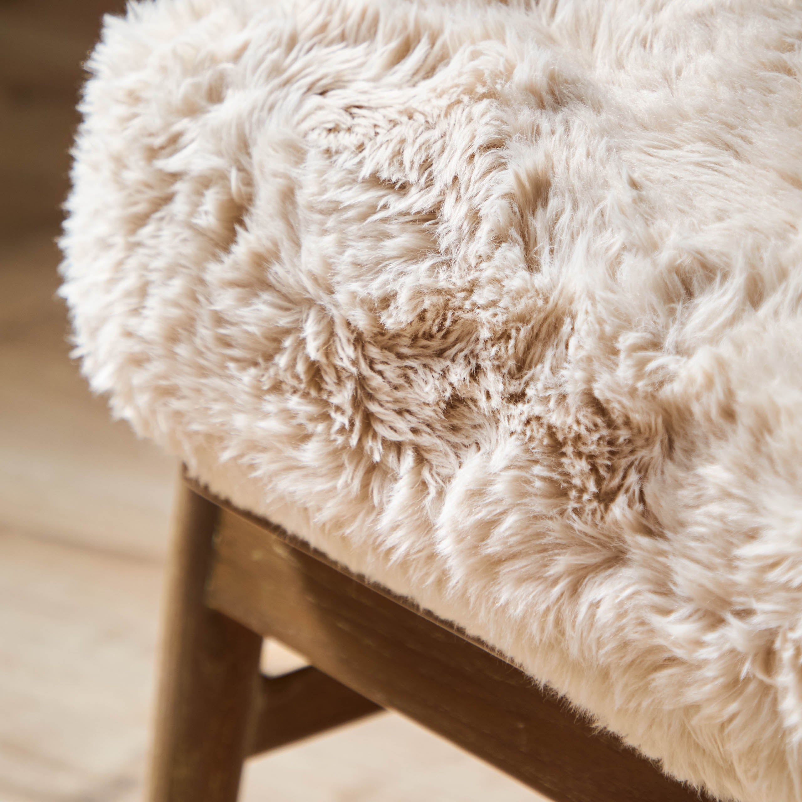 Close-up of Struan accent chair natural textured upholstery and solid oak frame against a softly blurred wood floor