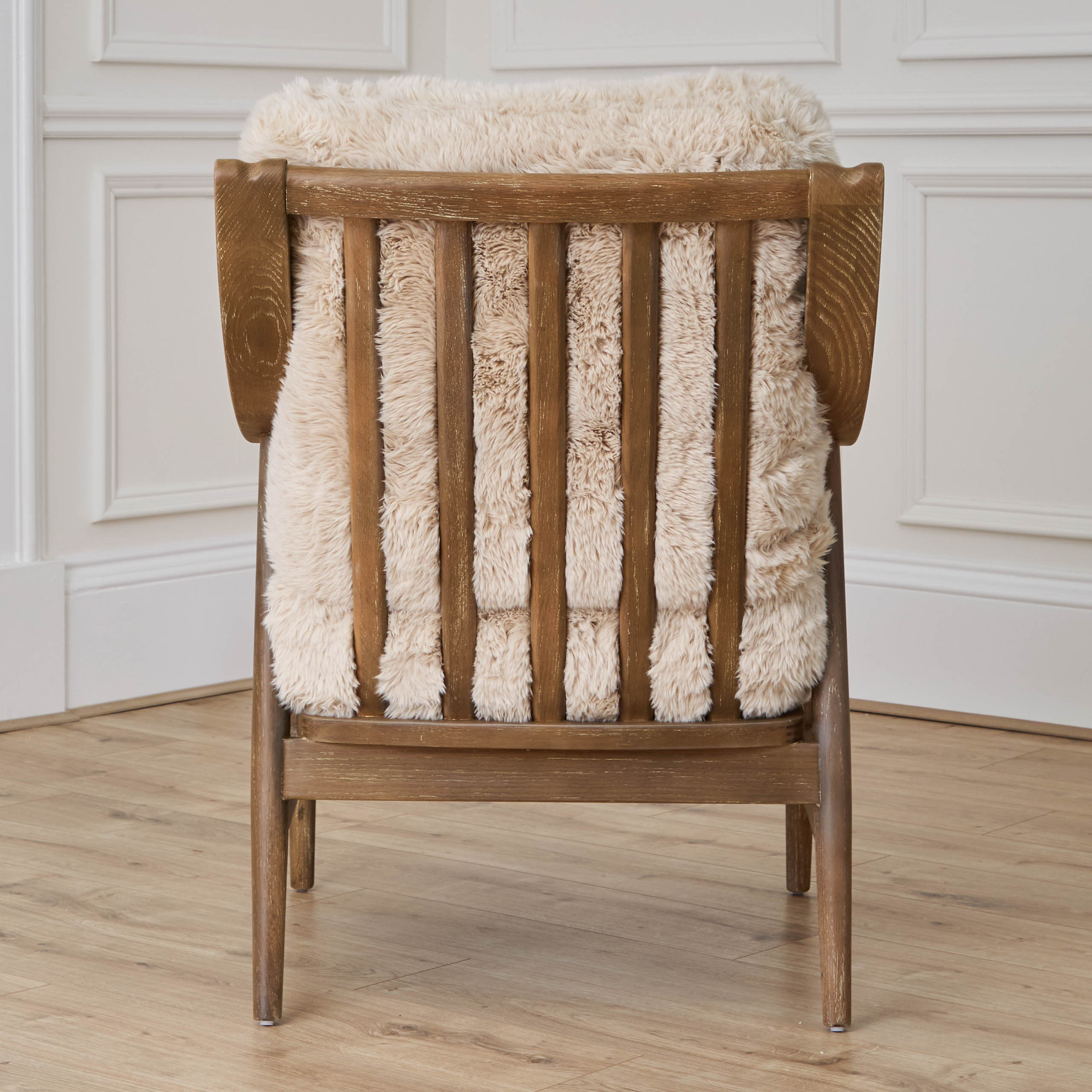 Rear view of Struan solid oak accent chair with natural upholstery, white panelled walls and light wood floor