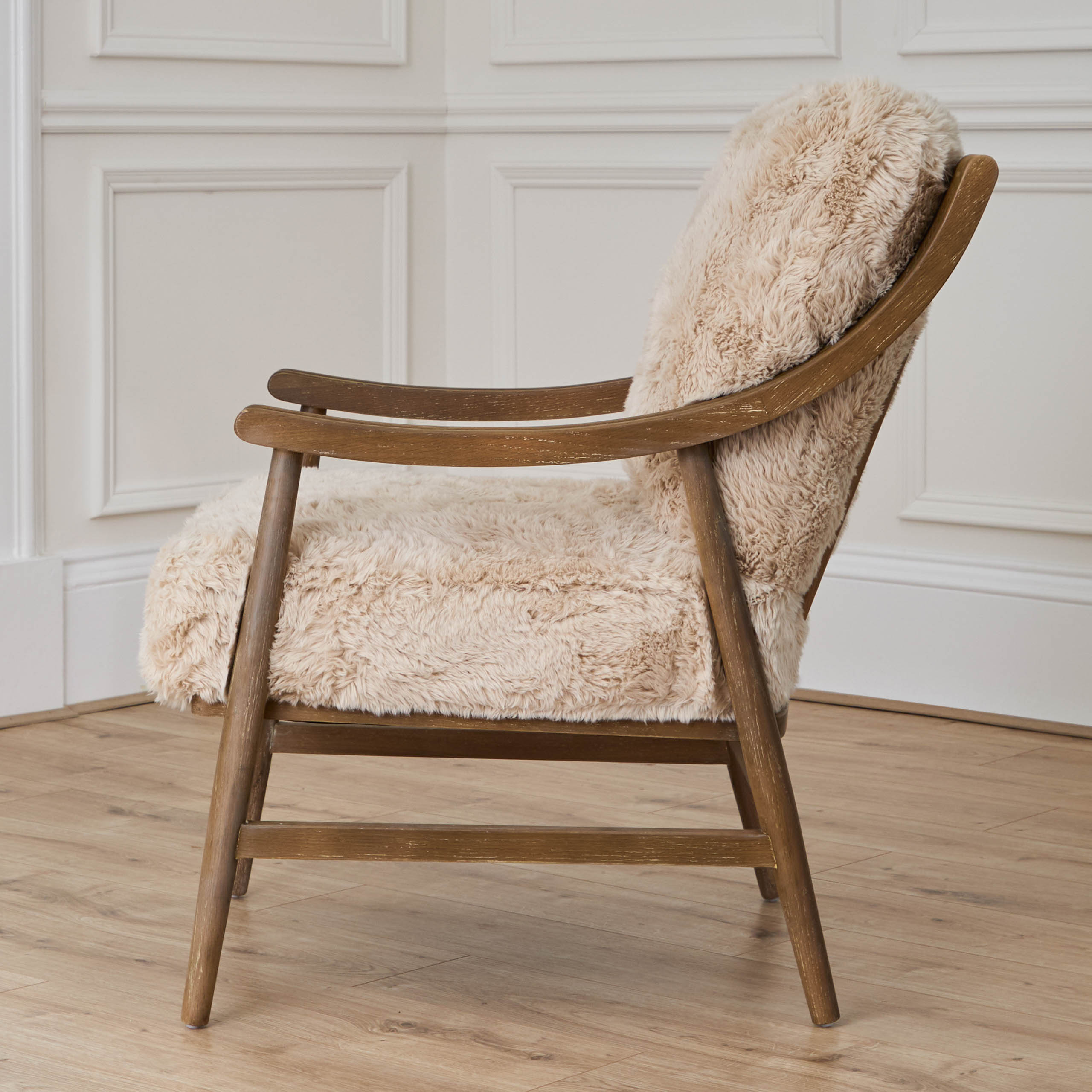 Struan solid oak upholstered accent chair, side view against white panelled walls and light wood flooring