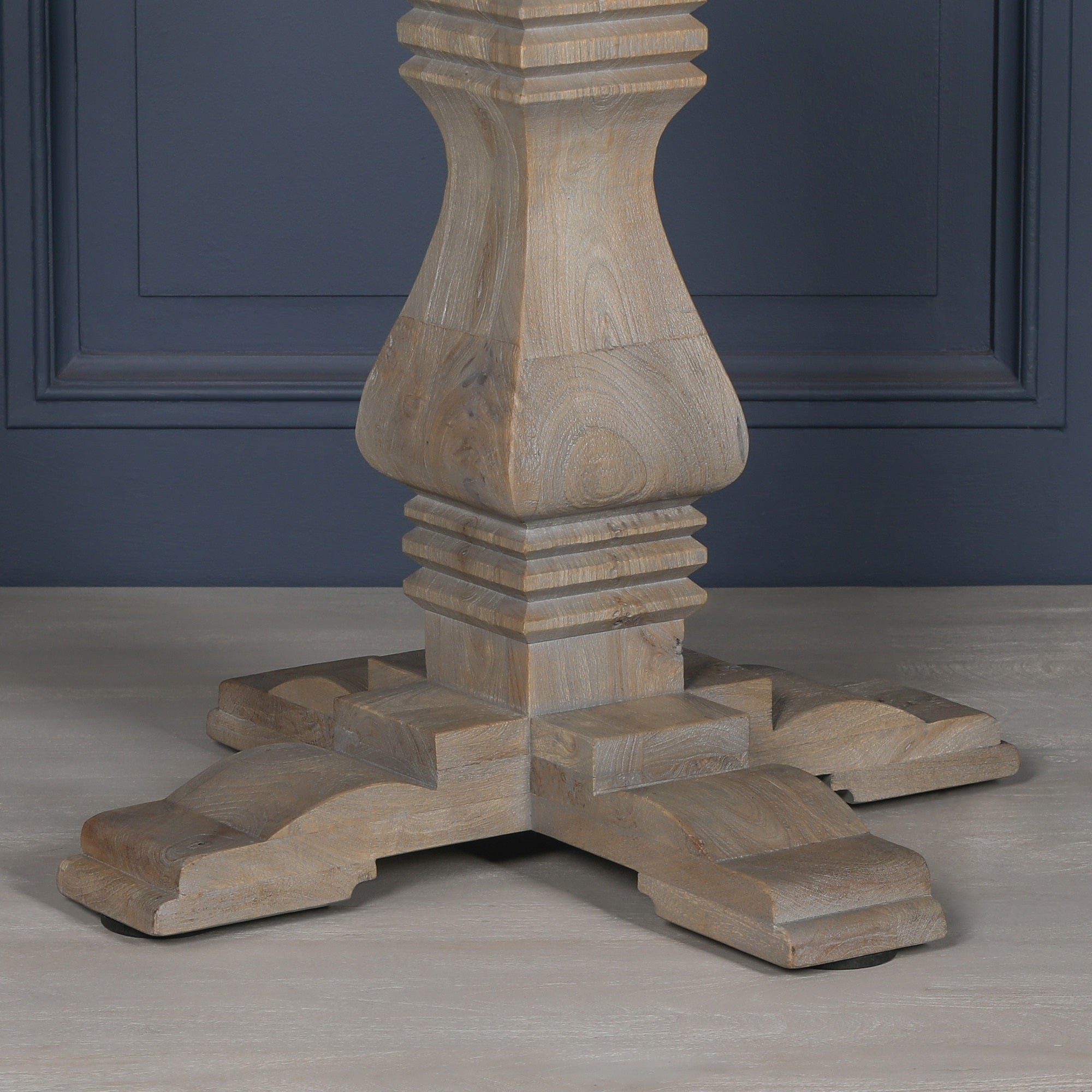 Close-up of the sculptural pedestal base on the Théodore Round Pedestal Dining Table for 6, featuring carved architectural detailing, solid wood craftsmanship, rustic white cedar style finish and substantial cross-foot support.