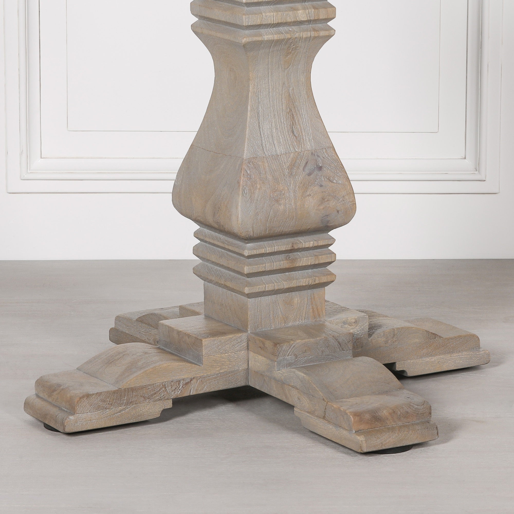 Detailed close-up of the handcrafted pedestal base on the Théodore Round Pedestal Dining Table for 6, highlighting the architectural carved design, solid wood construction, rustic white cedar style finish and traditional craftsmanship.