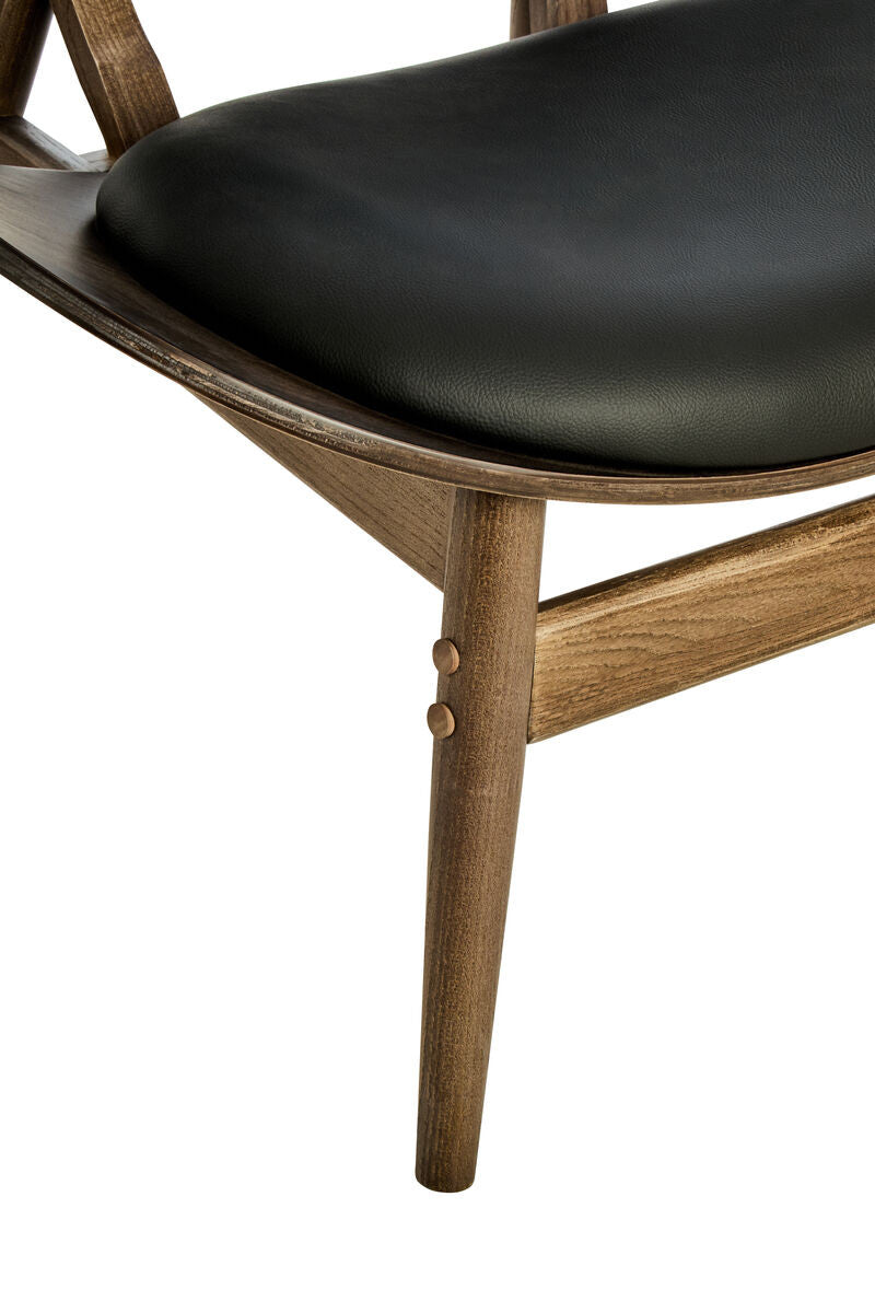 Close-up of the Vincent Tufted Lounge Chair showcasing the padded black leather effect seat, curved solid elm wood frame, premium upholstery finish and precision-crafted joinery.