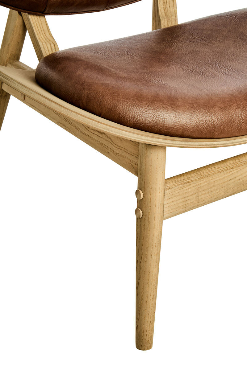 Detailed close-up of the Vincent Tufted Lounge Chair featuring the generously padded brown leather effect seat, curved solid elm wood frame and precision-crafted joinery.